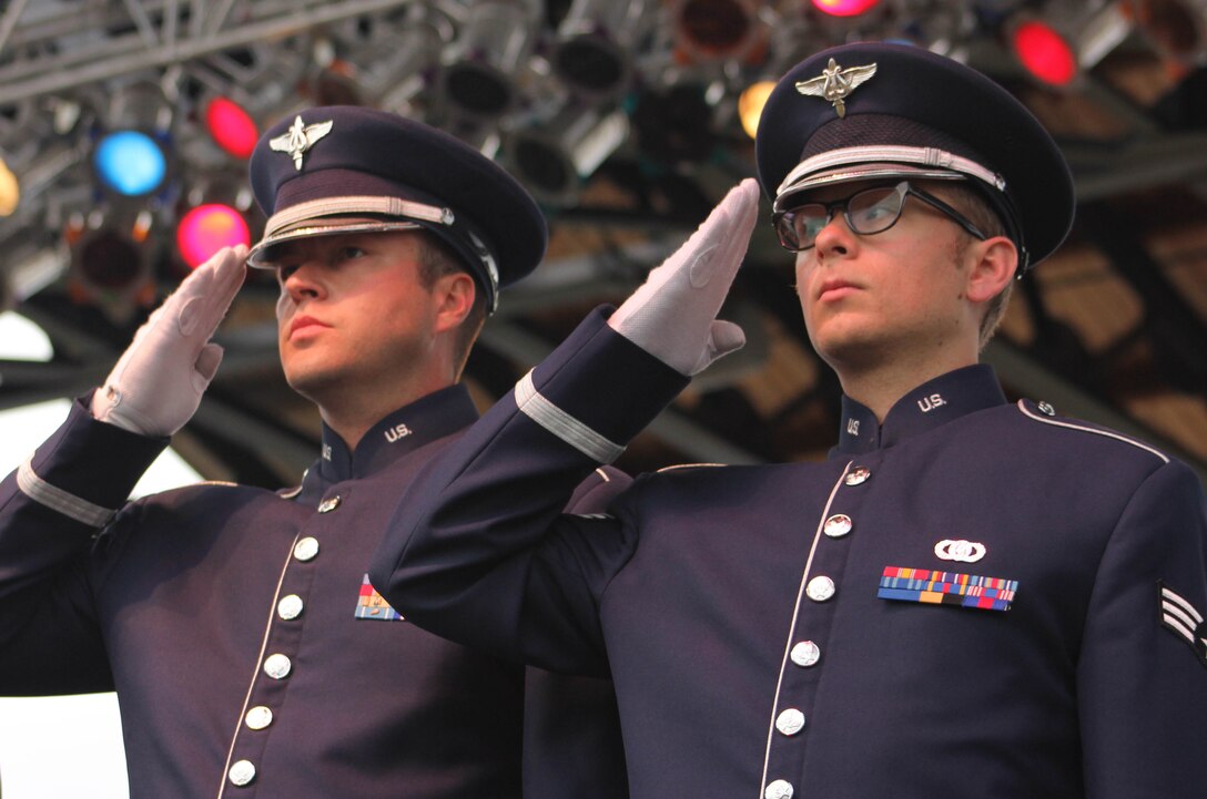 From left, U.S. Air Force Staff Sgt. Scott A. Parsons and Senior Airman Devin P. Larue, both instrumentalists with the 566th Air Force Band, salute as the Air National Guard Band of the Midwest performs The Star-Spangled Banner during annual training at the Bayfront Festival Park, Duluth, Minn., July 4, 2014. They performed jazz, rock and concert music for audiences in Illinois and Wisconsin as part of their community relations tour before a grand finale in Minnesota July 4. The annual concert series was the result of a year’s worth of training and practice, one that the band used to celebrate patriotism with communities across the Midwest. (Courtesy photo/Released)