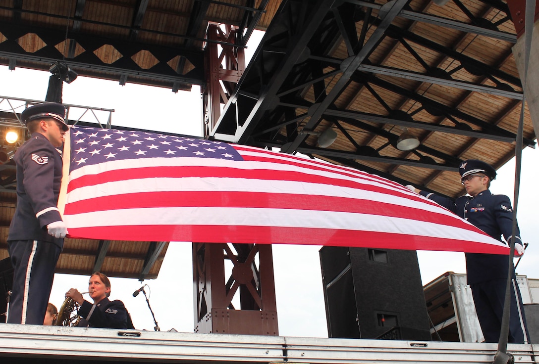 From left, U.S. Air Force Staff Sgt. Scott A. Parsons and Senior Airman Devin P. Larue, both instrumentalists with the 566th Air Force Band, conduct a flag-folding ceremony while the Air National Guard Band of the Midwest performs for audiences during annual training at the Bayfront Festival Park, Duluth, Minn., July 4, 2014. They performed jazz, rock and concert music for audiences in Illinois and Wisconsin as part of their community relations tour before a grand finale in Minnesota July 4. The annual concert series was the result of a year’s worth of training and practice, one that the band used to celebrate patriotism with communities across the Midwest. (Courtesy photo/Released)