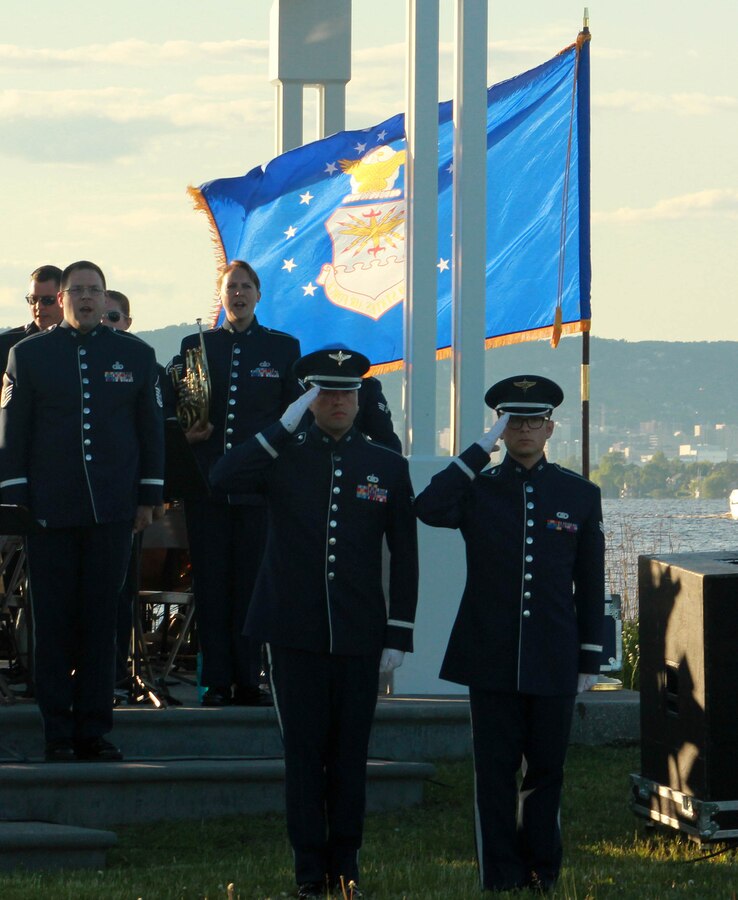 From left, U.S. Air Force Staff Sgt. Scott A. Parsons and Senior Airman Devin P. Larue, both instrumentalists with the 566th Air Force Band, salute as the Air National Guard Band of the Midwest performs The Star-Spangled Banner for audiences during annual training at Barker’s Island Festival Park, Superior, Wis., July 3, 2014. They performed jazz, rock and concert music for audiences in Illinois and Wisconsin as part of their community relations tour before a grand finale in Minnesota July 4. The annual concert series was the result of a year’s worth of training and practice, one that the band used to celebrate patriotism with communities across the Midwest. (Courtesy photo/Released)
