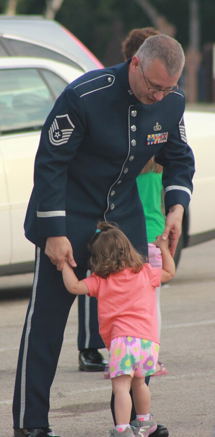 U.S. Air Force Master Sgt. James D. Barnard, instrumentalist with the 566th Air Force Band, dances with a child as the National Guard Band of the Midwest performs for audiences during annual training at the Grundy County Courtyard Lawn, Morris, Ill., June 29, 2014. They performed jazz, rock and concert music for audiences in Illinois and Wisconsin as part of their community relations tour before a grand finale in Minnesota July 4. The annual concert series was the result of a year’s worth of training and practice, one that the band used to celebrate patriotism with communities across the Midwest. (Courtesy photo/Released)