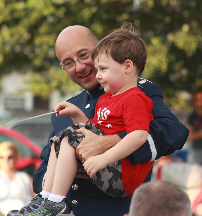 U.S. Air Force Maj. Bryan M. Miller helps a boy conduct the Air National Guard Band of the Midwest while it performs for audiences during annual training at the Grundy County Courtyard Lawn, Morris, Ill., June 29, 2014. They performed jazz, rock and concert music for audiences in Illinois and Wisconsin as part of their community relations tour before a grand finale in Minnesota July 4. The annual concert series was the result of a year’s worth of training and practice, one that the band used to celebrate patriotism with communities across the Midwest. (Courtesy photo/Released)