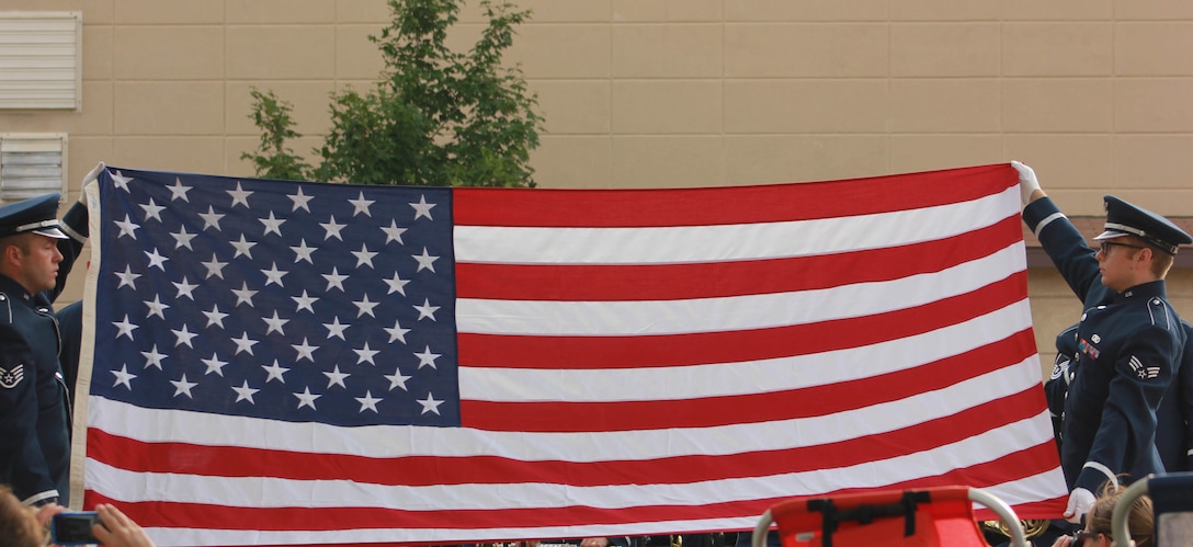 From left, U.S. Air Force Staff Sgt. Scott A. Parsons and Senior Airman Devin P. Larue, both instrumentalists with the 566th Air Force Band, conduct a flag-folding ceremony during the Air National Guard Band of the Midwest's annual training at the Grundy County Courtyard Lawn, Morris, Ill., June 29, 2014. They performed jazz, rock and concert music for audiences in Illinois and Wisconsin as part of their community relations tour before a grand finale in Minnesota July 4. The annual concert series was the result of a year’s worth of training and practice, one that the band used to celebrate patriotism with communities across the Midwest. (Courtesy photo/Released)