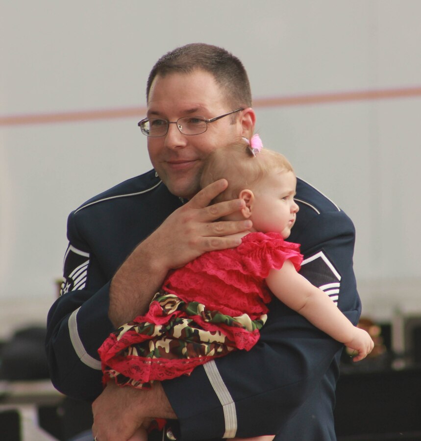 U.S. Air Force Master Sgt. John F. Kinsella, instrumentalist with the 566th Air Force Band, dances with his daughter while the Air National Guard Band of the Midwest performs for audiences during annual training at the Grundy County Courtyard Lawn, Morris, Ill., June 29, 2014. They performed jazz, rock and concert music for audiences in Illinois and Wisconsin as part of their community relations tour before a grand finale in Minnesota July 4. The annual concert series was the result of a year’s worth of training and practice, one that the band used to celebrate patriotism with communities across the Midwest. (Courtesy photo/Released)