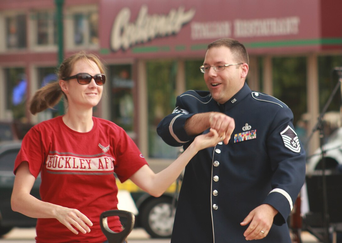 U.S. Air Force Master Sgt. John F. Kinsella, instrumentalist with the 566th Air Force Band, dances with his wife while the Air National Guard Band of the Midwest performs for audiences during annual training at the Grundy County Courtyard Lawn, Morris, Ill., June 29, 2014. They performed jazz, rock and concert music for audiences in Illinois and Wisconsin as part of their community relations tour before a grand finale in Minnesota July 4. The annual concert series was the result of a year’s worth of training and practice, one that the band used to celebrate patriotism with communities across the Midwest. (Courtesy photo/Released)