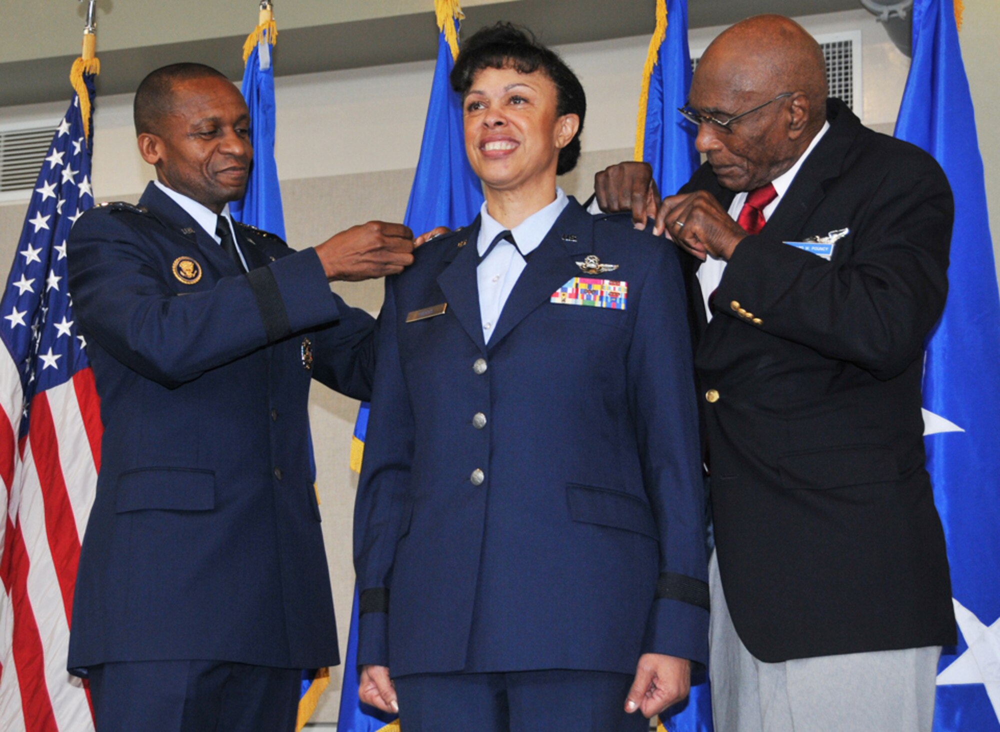 Gen. Darren W. McDew, Air Mobility Command commander, and Hillard W. Pouncy, an original Tuskegee Airman, pin stars on Harris during her recent promotion ceremony. (Staff Sgt. Jaclyn McDonald)