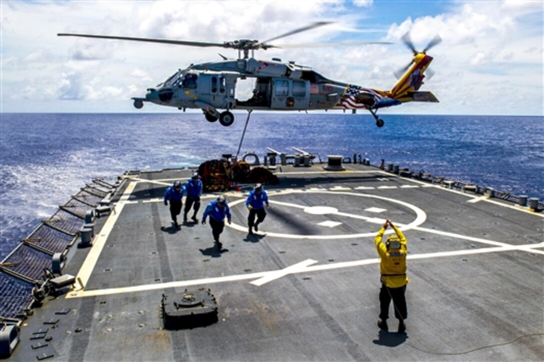 U.S. sailors aboard the guided missile destroyer USS Fitzgerald move to safer location as a MH-60S Seahawk helicopter picks up supplies from the ship's flight deck during Valiant Shield 2014 in the Pacific Ocean, Sept. 20, 2014.