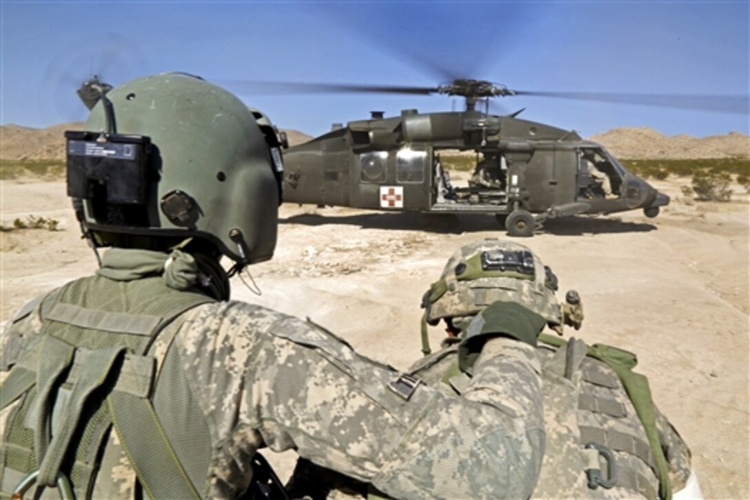 A crew chief directs soldiers carrying a simulated patient to a UH-60 Black Hawk medevac helicopter during an evacuation exercise as part of Decisive Action Rotation 14-10 at the National Training Center on Fort Irwin, Calif., Sept. 13, 2014. The exercise provides a comprehensive approach to training brigade combat teams in a multinational environment. 