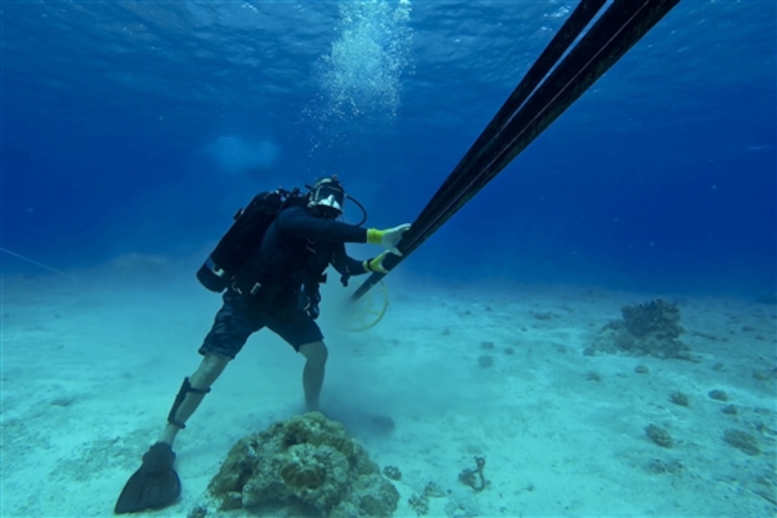 U.S. Navy Petty Officer 1st Class Leroy Schnathorst guides subsea cables through a horizontally directionally drilled conduit at the Kwajelein Missile Impact Scoring System Range in Gagan, Marshall Islands, Sept. 8, 2014. The Underwater Construction Team 2 Construction Dive Detachment Alpa is deployed to the Pacific region inspecting, maintaining and repairing various underwater and waterfront facilities in support of the U.S. Pacific Fleet. 