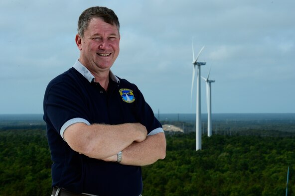 Steve Mellin, 6th Space Warning Squadron support officer, stands before two wind turbine power generators on Cape Cod Air Force Station, Mass., Sept. 11, 2014. The two wind turbines provide Cape Cod AFS with nearly 50 percent of their power needs and helps save the Air Force more than $600,000 annually. (U.S. Air Force photo by Airman 1st Class Krystal Ardrey)