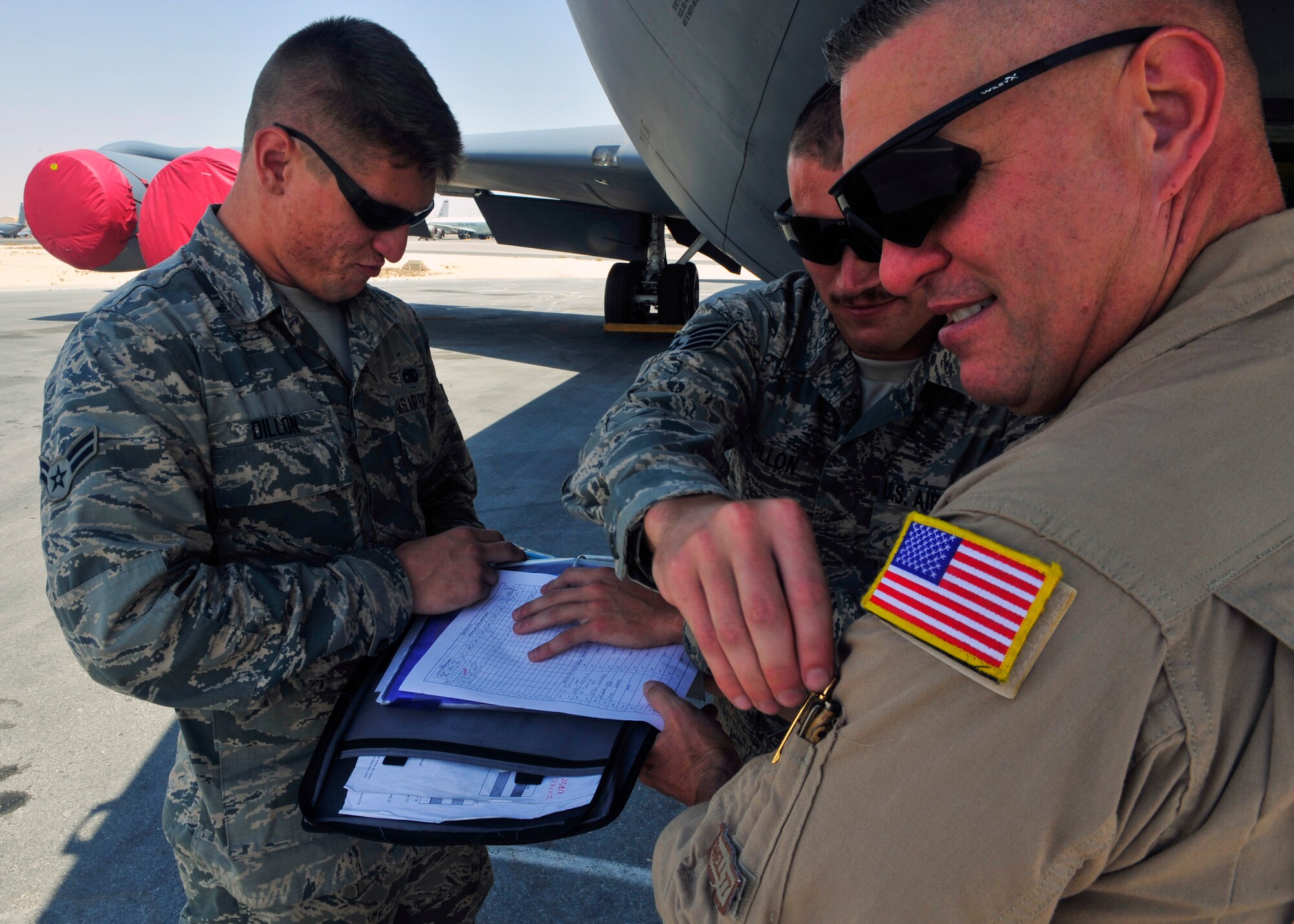 U.S. Air Force Staff Sgt. Matthew Dillon, 379th Expeditionary Aircraft Maintenance Squadron crew chief, pulls a pen from Senior Master Sgt. Brian Dillon’s 340th Expeditionary Air Refueling Squadron boom operator, pocket, while Airman 1st Class Adam Dillon, 379th Expeditionary Aircraft Maintenance Squadron crew chief holds a preflight checklist at Al Udeid Air Base, Qatar, Sept. 20, 2014. Father, Brian Dillon and his two sons Matthew and Adam have more than 40 years of service together and are deployed combined for the first time. The Dillon’s are deployed from the 190th Air Refueling Wing in Topeka, Kansas. Their hometown is Niagara Falls, New York. (U.S. Air Force photo by Senior Airman Colin Cates) 