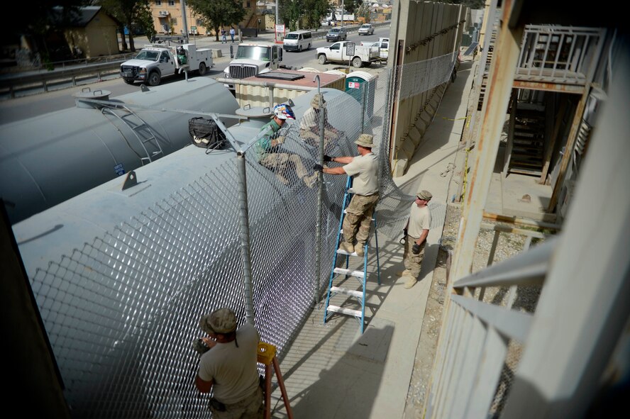 U.S. Air Force Airmen with the 455th Expeditionary Civil Engineer Squadron build a fence at Bagram Airfield, Afghanistan Spet. 19, 2014.  The Airmen have been working on  a security project for several days. As Civil Engineer Airmen they are responsible for maintaining structures and utilities.  (U.S. Air Force photo by Staff Sgt. Evelyn Chavez/Released)