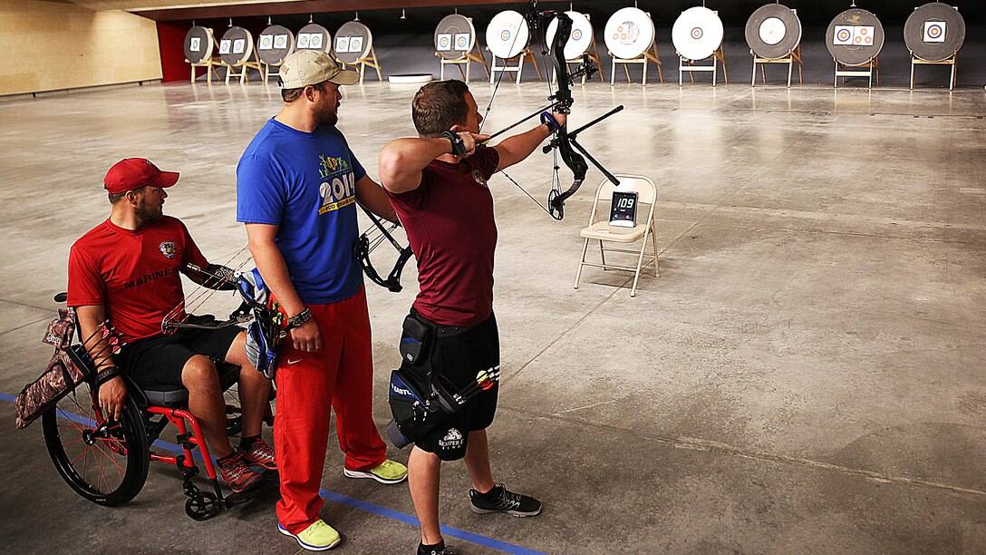 Sgt. Allen Melick, from Brighton, Michigan, aims down range with his teammates; Sgt. Clayton McDaniel from Molalla, Oregon (center) and Cpl. Richard Stalder from Muenster, Texas (right) during archery practice for the Marine team, September 24, in preparation for the 2014 Warrior Games. The Marine team has been training since September 15 in order to build team cohesion and acclimate to the above 6,000 ft. altitude of Colorado Springs. The Marine team is comprised of both active duty and veteran wounded, ill and injured Marines who are attached to or supported by the Wounded Warrior Regiment, the official unit of the Marine Corps charged with providing comprehensive non-medical recovery care to wounded, ill and injured Marines.