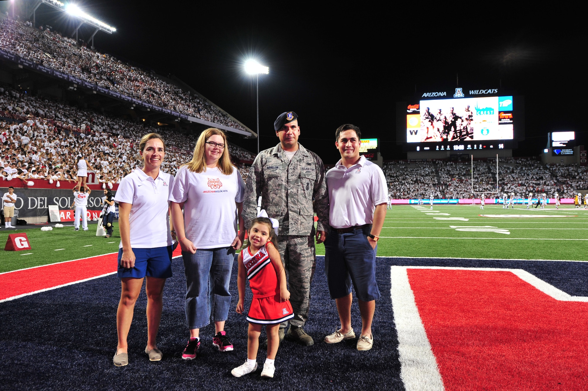 U.S. Air Force Senior Airman Joshua Aguillon, 355th Security Forces Squadron member, stands with his family and event sponsors while being honored during a “Welcome Home Hero” ceremony at Arizona Stadium, Tucson, Ariz., Sept. 20, 2014.  With a different branch being recognized each week since 2012, the ceremony honors a service member who was chosen by their branch for having a deployment record that stood out among the rest.  (U.S. Air Force Photo by Airman 1st Class Chris Massey/Released)
