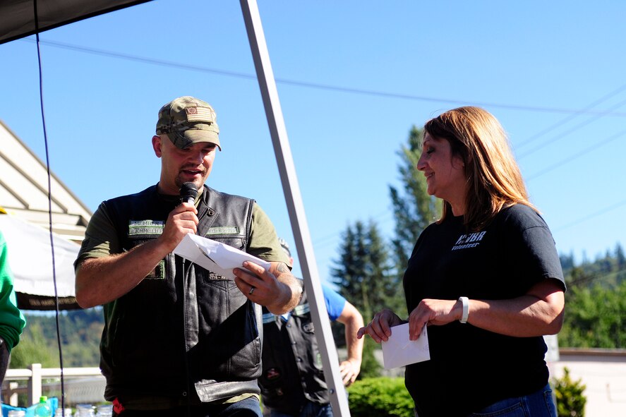 Tech. Kevin Beers, 446th Security Forces Squadron combat arms instructor, gives Kim Hamilton, Northwest Boxer Rescue organization board of director’s member, the donations earned from the Poker Run motorcycle ride Sept. 9, 2014, in Eatonville, Wash. The Poker Run was the Green Knights Military Motorcycle Club’s first off-base charity event, but the club participates in more than 15 charity events annually, as well as bi-annual maintenance seminars and motorcycle sustainment training classes for the 62nd Airlift Wing. (U. S. Air Force photo/Senior Airman Rebecca Blossom)

