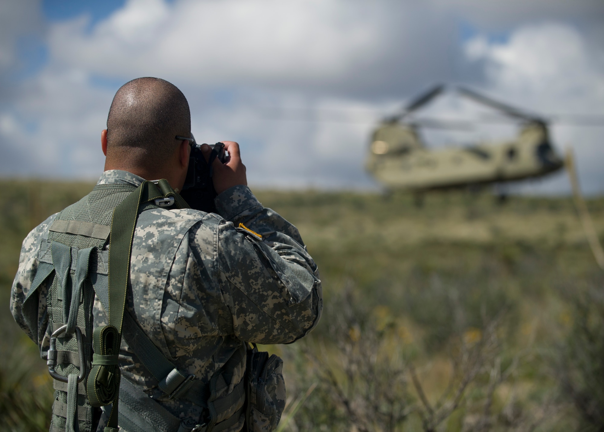 U.S. Army Sgt. Duncan Brennan, Public Affairs specialist, public affairs noncommissioned officer in charge, 101st Combat Aviation Brigade, 101st Airborne Division (Air Assault), takes photos of a U.S. Army CH-47 Chinook performing training on a mountain-top over Fort Bliss, Texas, Sept. 23. Soldiers from the 101st Airborne Division use the Holloman and White Sands Missile Range training ranges to conduct a Hostile Environment Medical Training Course, designed specifically for Close Protection Operations during deployments to high threat regions throughout the world. (U.S. Air Force photo by Senior Airman Leah Ferrante/Released)