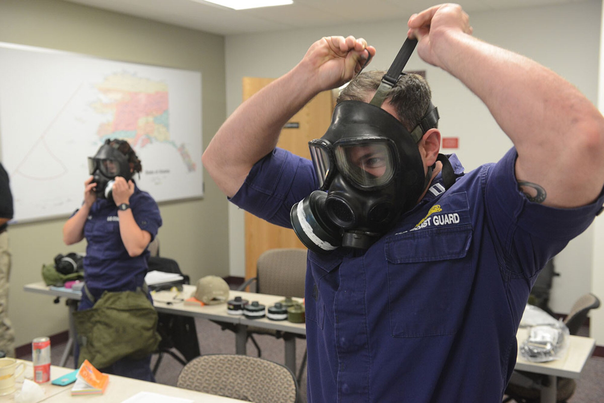 Coast Guard Lt. Aaron Renschler from the Sector Anchorage, Alaska, enforcement division dons a protective mask during domestic egress training at Sector Anchorage Sept. 9, 2014. Personnel in the class learned how to properly and quickly use safety equipment in the event of a hazardous material threat. (U.S. Coast Guard photo by Petty Officer 1st Class Shawn Eggert)