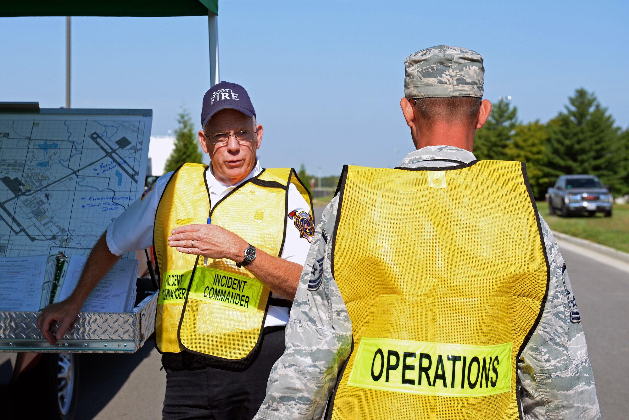 Paul Kempton, 375th Civil Engineering Squadron deputy fire chief discusses strategy at the temporary command station during a simulated fuel spill exercise at Scott Air Force Base, Ill., Sept. 25, 2014. The 126th Air National Guard’s fuel tanks had a simulated leaking valve. Kempton communicated with firefighters via radio to relay how to best tackle the fuel spill. The WIT observed the actions of the participating players and suggested the players went through the scenario just as they would do in real life to get the most out of the exercise and find efficient ways to utilize the participating organizations.  (U.S. Air Force photo by Airman 1st Class Erica Crossen)