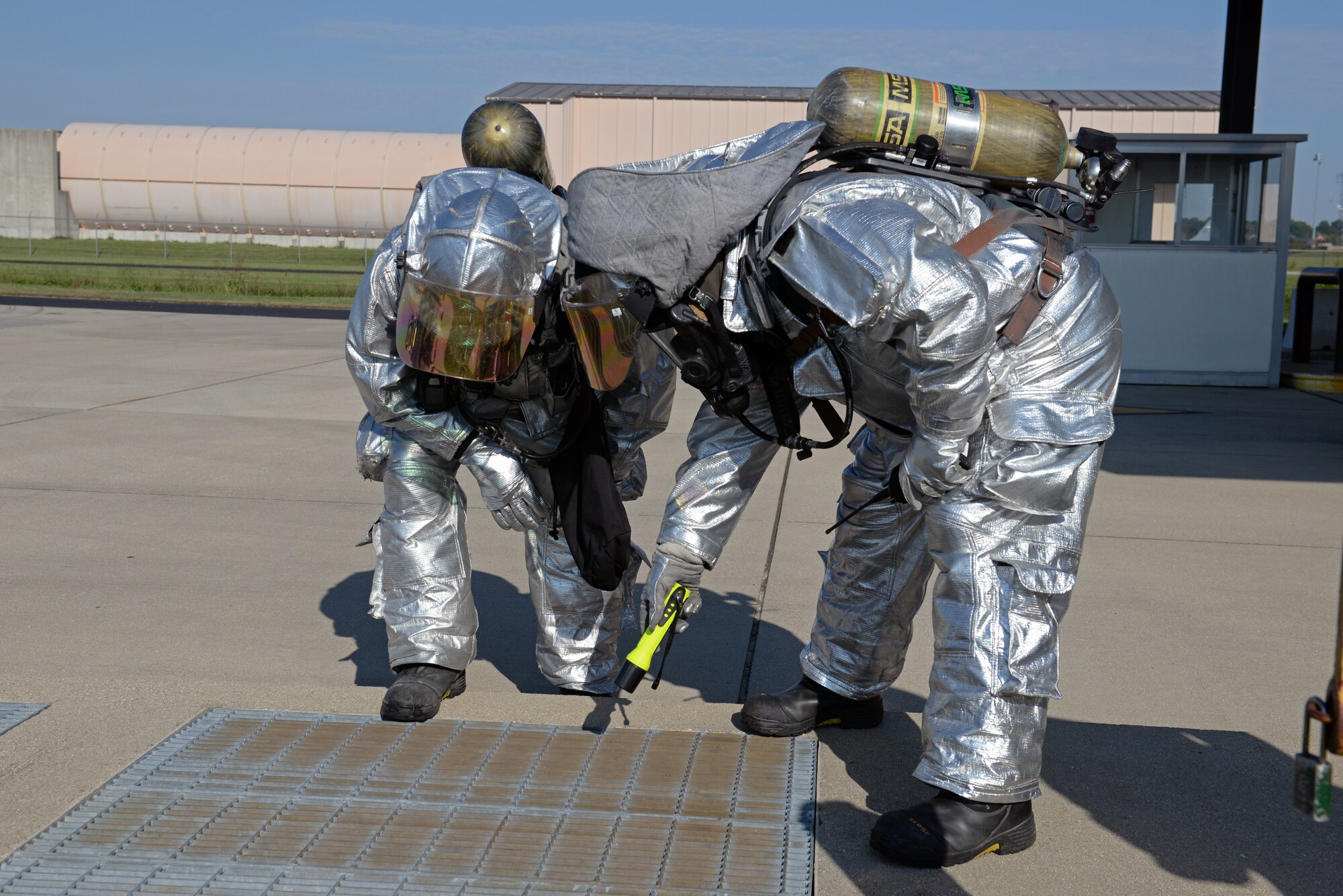 William Johnson, 375th Civil Engineering Squadron station captain, and Staff Sgt. Eric Butler, firefighter, look for evidence of fuel in the water drainage system during a simulated fuel spill at Scott Air Force Base, Ill., Sept. 25, 2014. The 126th Air National Guard’s fuel tanks had a simulated leaking valve. Under a ticking clock, 375 CES, bioenvironmental, security forces, and other base resources converged to quickly mitigate the problem. The Wing Inspection Team observed the actions of the participating players and suggested the players went through the scenario just as they would do in real life to get the most out of the exercise. (U.S. Air Force photo by Airman 1st Class Erica Crossen)