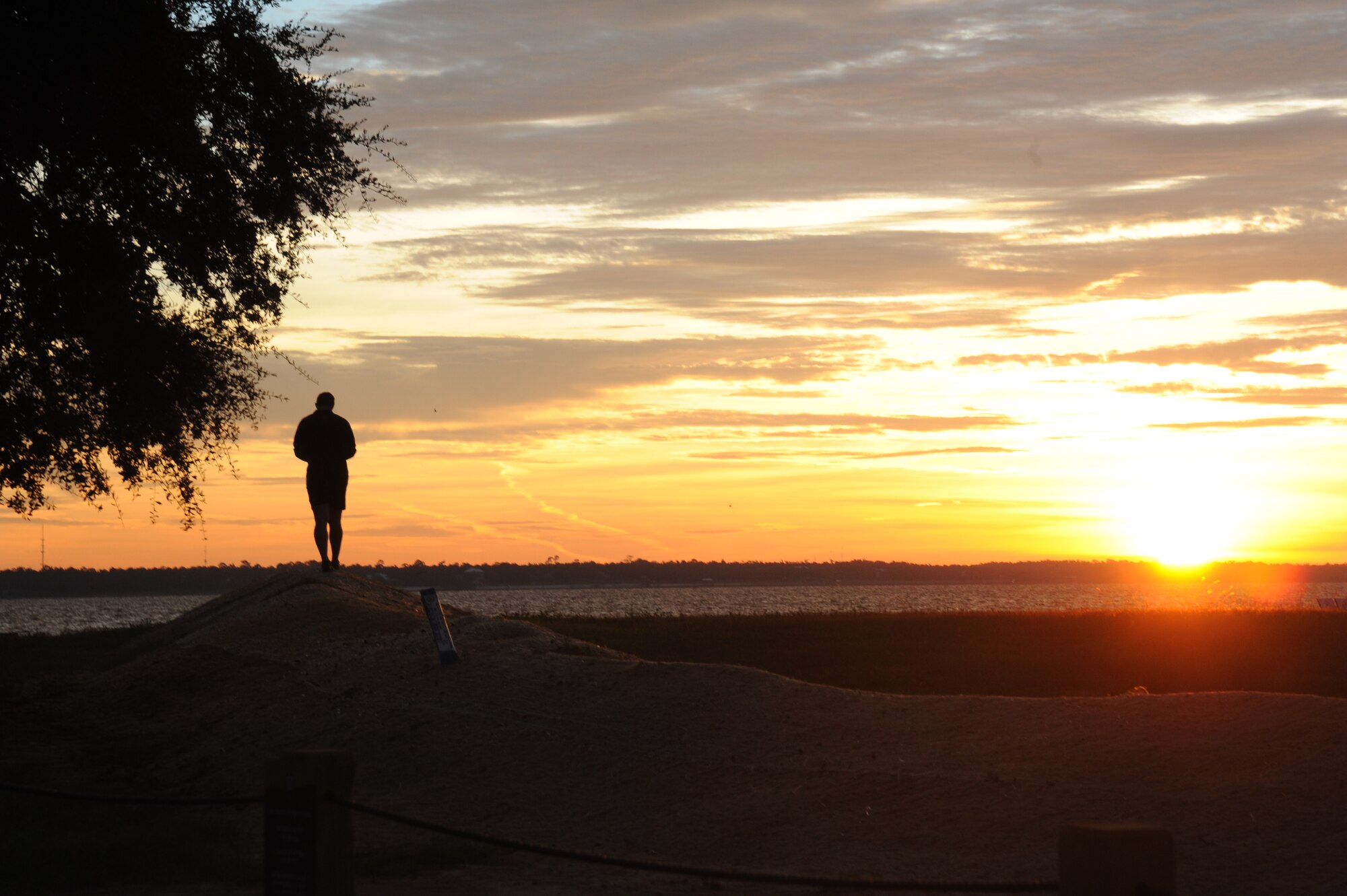 An instructor from the 334th Training Squadron combat controllers stands near the foot of the Biloxi/Ocean Springs Bridge as he waits on Keesler’s battlefield Airmen as they participate in a memorial physical training session Sept. 26, 2014, Biloxi, Miss., with a ruck march along the Ocean Springs Beach and over the Biloxi/Ocean Springs Bridge. The PT event was in memory of combat controller Senior Airman Mark Forester who was killed in action Sept. 29, 2010, and Senior Airman Daniel Sanchez who was killed in action Sept. 16, 2010.  (U.S. Air Force photo by Kemberly Groue)