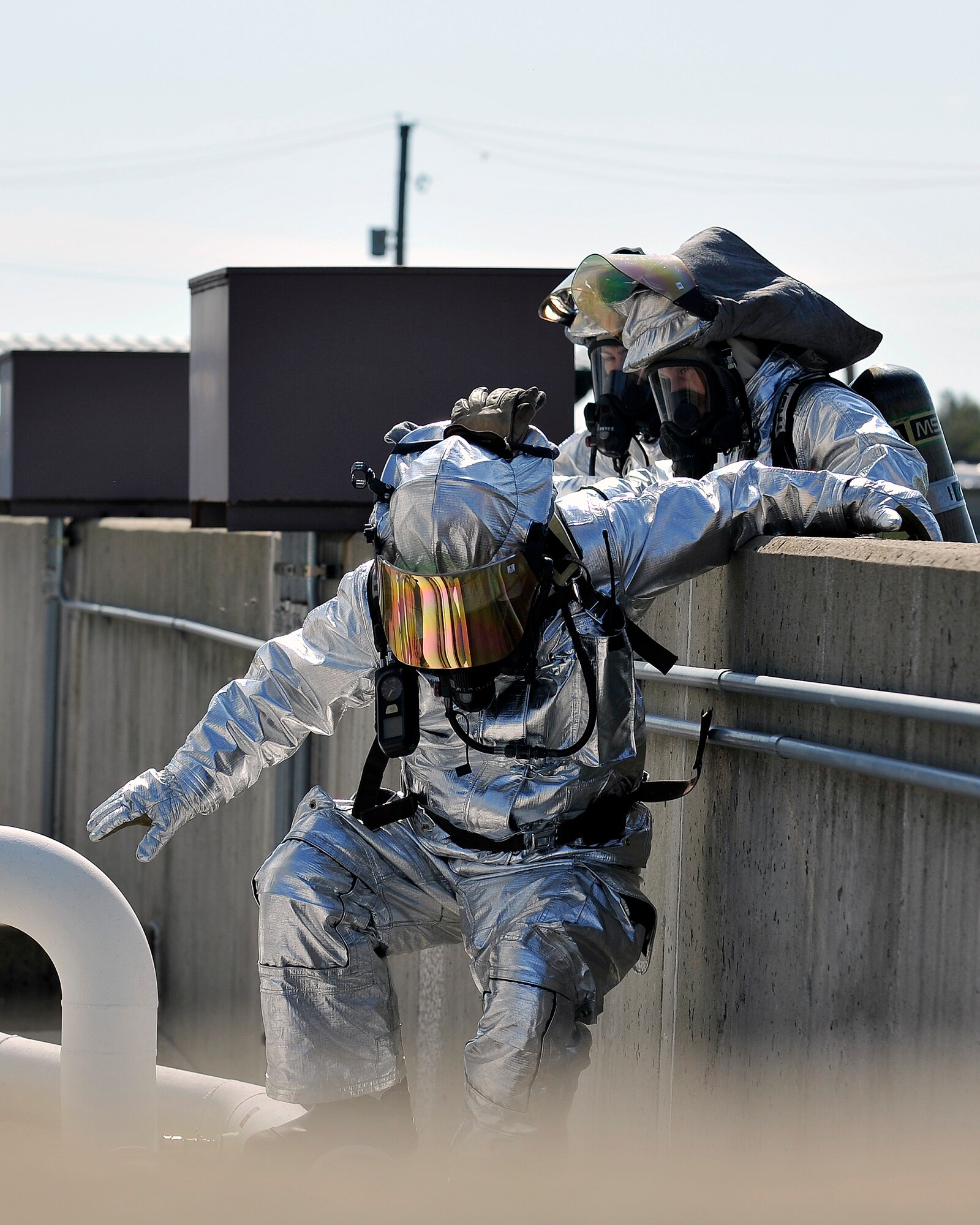 Tobias Midkiff, 375th Civil Engineering Squadron station chief, climbs over the barrier to the simulated leaking fuel tank to shut off a broken valve at the 126th Air National Guard’s fuel tanks at Scott Air Force Base, Ill., Sept. 25, 2014. The 375th Air Mobility Wing Inspection Team observed the exercise, to ensure the most efficient approaches were taken to resolve the problem. The firefighters analyzed the problem, and practiced what they would do in a real life emergency.  (U.S. Air Force photo by Airman 1st Class Erica Crossen)