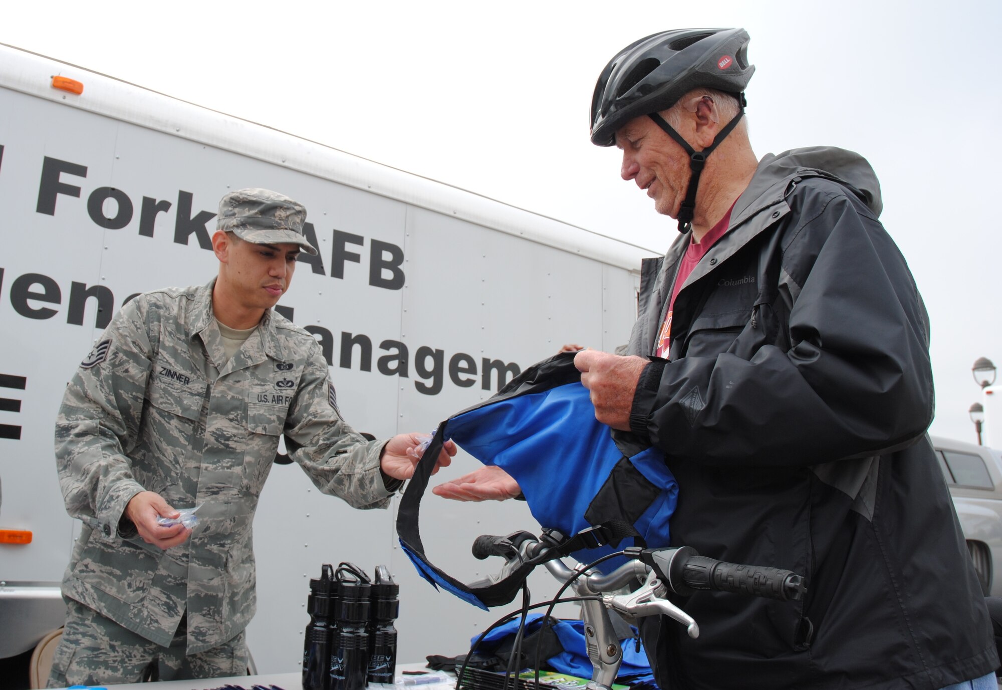 Staff Sgt. Shaun Zinner from the 319th Civil Engineering Squadron’s Emergency Management Flight hands retired Chief Master Sgt. Basil Nosal a few goodies and information on creating an emergency preparedness kit Sept. 25, 2014, in the Exchange parking lot on Grand Forks Air Force Base, N.D.  Airmen from the 319th CES EMF raised awareness about National Preparedness Months by set up static displays with EMF vehicles and information booths at the Exchange September 25-26. They spoke to dozens of Exchange patrons that included uniformed personnel, dependents and retirees.  National Preparedness Month is a part of a governmental effort to strengthen the United States' preparedness capabilities. The national preparedness architecture encompasses prevention, protection, response, and recovery efforts to prepare the United States for all hazards – whether terrorist attack or natural disaster. (U.S. Air Force photo/Staff Sgt. Luis Loza Gutierrez)
