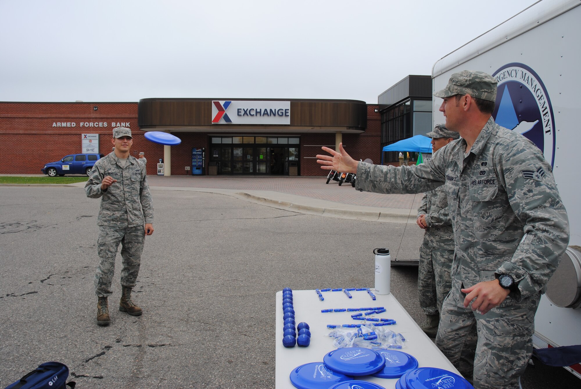 Senior Airman Scott Tucker from the 319th Civil Engineering Squadron’s Emergency Management Flight tosses an Air Force Be Prepared Frisbee to Airman 1st Class Brandon Nicholson Sept. 25, 2014, in the Exchange parking lot on Grand Forks Air Force Base, N.D.   Frisbees, stress balls, and pens were some of the goodies given out to Exchange patrons. September was chosen as National Preparedness Month, as the tragedies of September 11, 2001, highlighted to the nation the importance of being prepared. The 2014 National Preparedness Month theme is: “Be Disaster Aware, Take Action to Prepare.” (U.S. Air Force photo/Staff Sgt. Luis Loza Gutierrez)
