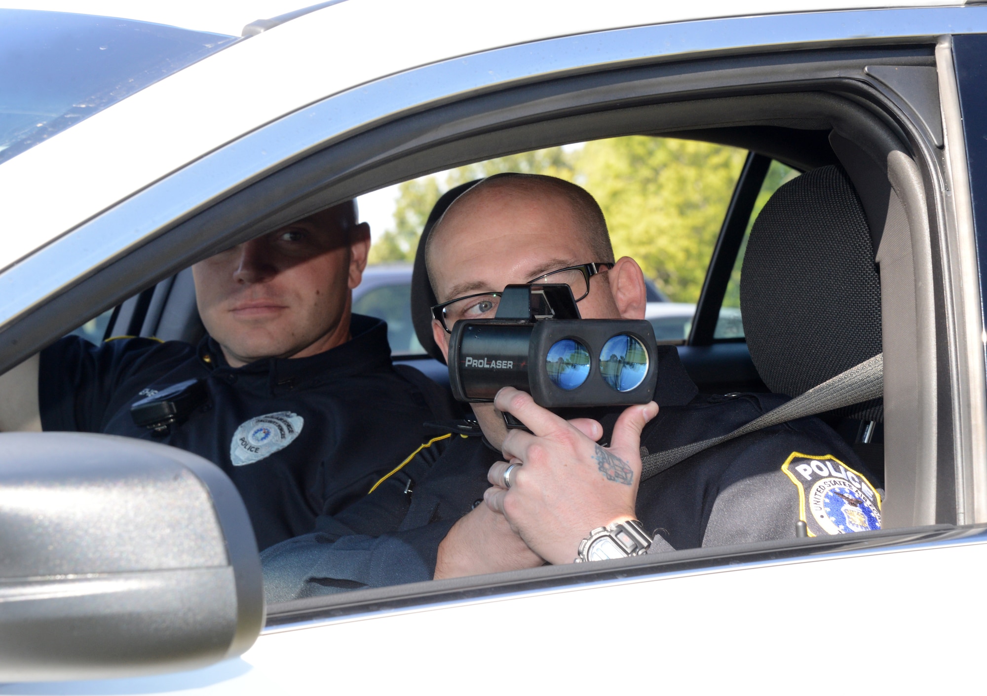 Sgt. Michael Biddy, front, and Corporal Aaron Whitehead use a radar gun to detect the speed limit of drivers on Tinker Air Force Base. The two DAF civilian police officers were both prior military before joining the civilian security forces here on base. Civilian officers are federally certified law enforcement officers and perform the same duties as the military security forces. (Air Force photo by Kelly White)
