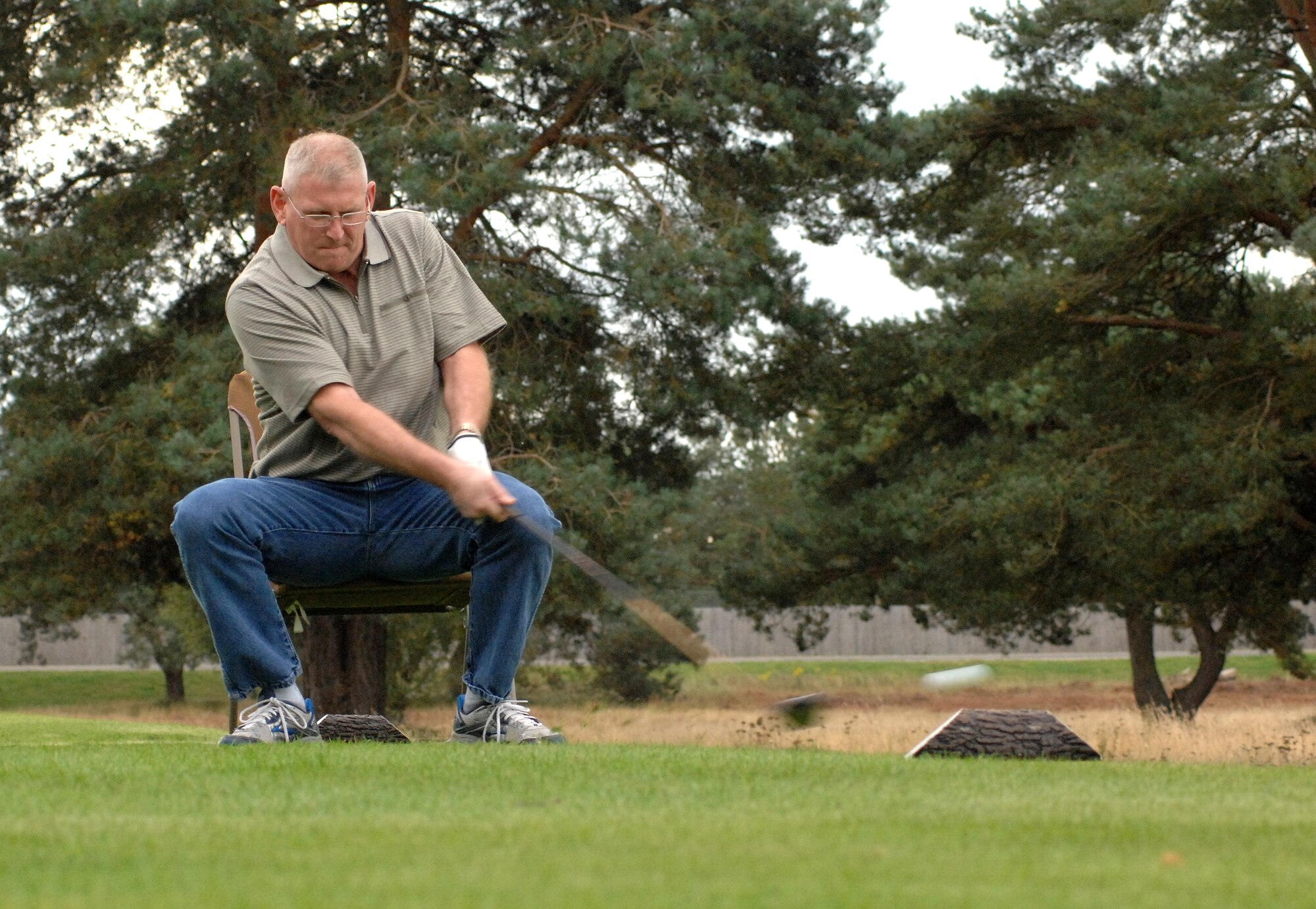 U.S. Air Force Chief Master Sgt. Donald Woods, 95th Reconnaissance Squadron chief enlisted manager from Huntsville, Mo., drives off the seventh hole sitting down in a lawn chair at the Chiefs vs. Eagles Golf Tournament Sept. 24, 2014, at the Breckland Pines Golf Club on RAF Lakenheath, England. On some tee boxes, golfers would have to play their shots using different props or equipment ranging from beer goggles and baseball bats to throwing a football. (U.S. Air Force photo/Gary Rogers/Released)