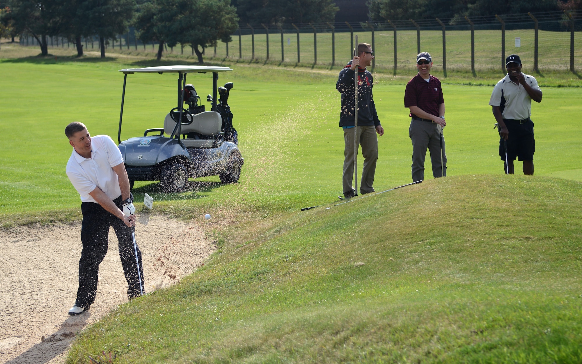 U.S. Air Force Senior Master Sgt. Sean Nelms, 100th Civil Engineer Squadron operations flight superintendent from Smithfield, Va., chips a ball out of a sand trap during the Chiefs vs. Eagles golf tournament Sept. 24, 2014, at the Breckland Pines Golf Club on RAF Lakenheath, England. The tournament was held to encourage teambuilding and morale among coworkers. (U.S. Air Force photo/Airman 1st Class Dillon Johnston/Released)