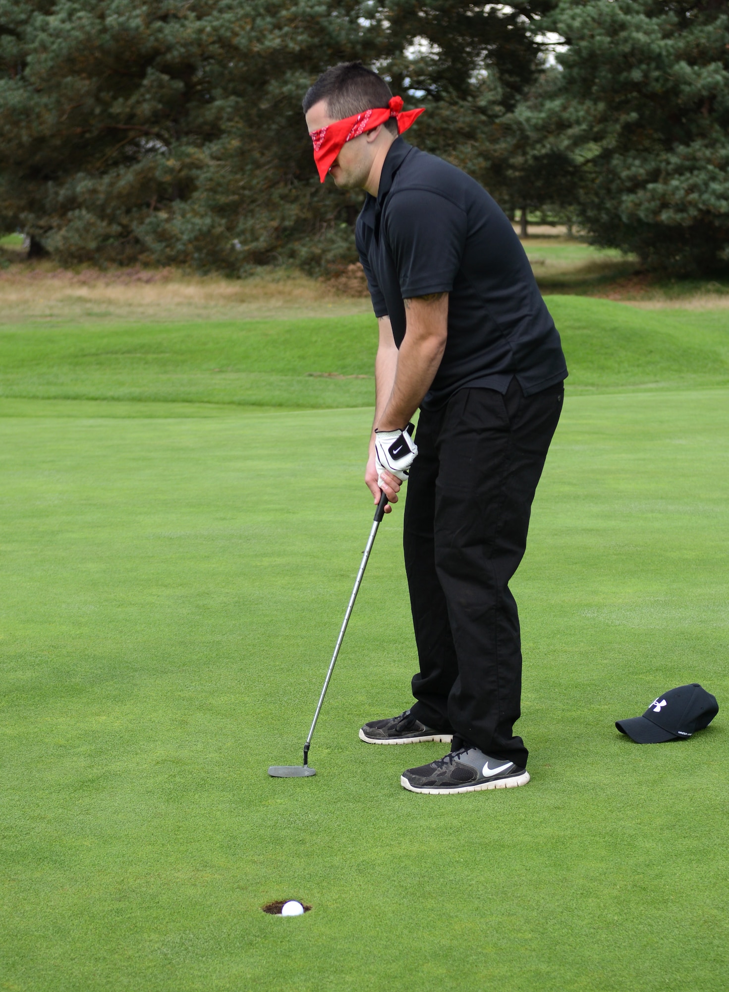 U.S. Air Force Staff Sgt. Dylan Matier, 100th Logistics Readiness Squadron equipment accountability supervisor from Los Angeles, sinks a putt while blindfolded during the Chiefs vs. Eagles golf tournament Sept. 24, 2014, at the Breckland Pines Golf Club on RAF Lakenheath, England. When the players got on the green, a blindfold was affixed over their eyes and they had to rely on their partner to tell them where to putt. (U.S. Air Force photo/Airman 1st Class Dillon Johnston/Released)