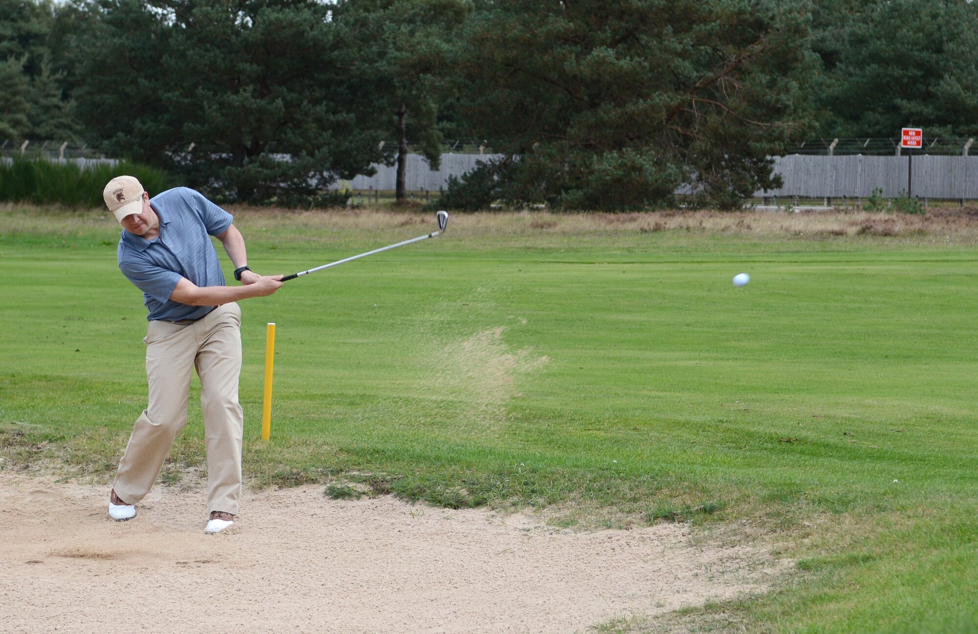 U.S. Air Force Maj. Glenn Cameron, 100th Civil Engineer Squadron operations flight commander from Roseville, Calif., chips a ball out of a sand trap during the Chiefs vs. Eagles golf tournament Sept. 24, 2014, at the Breckland Pines Golf Club on RAF Lakenheath, England. The sand trap was the starting point of the hole, one of the 18 different hole rules for the tournament. (U.S. Air Force photo/Airman 1st Class Dillon Johnston/Released)