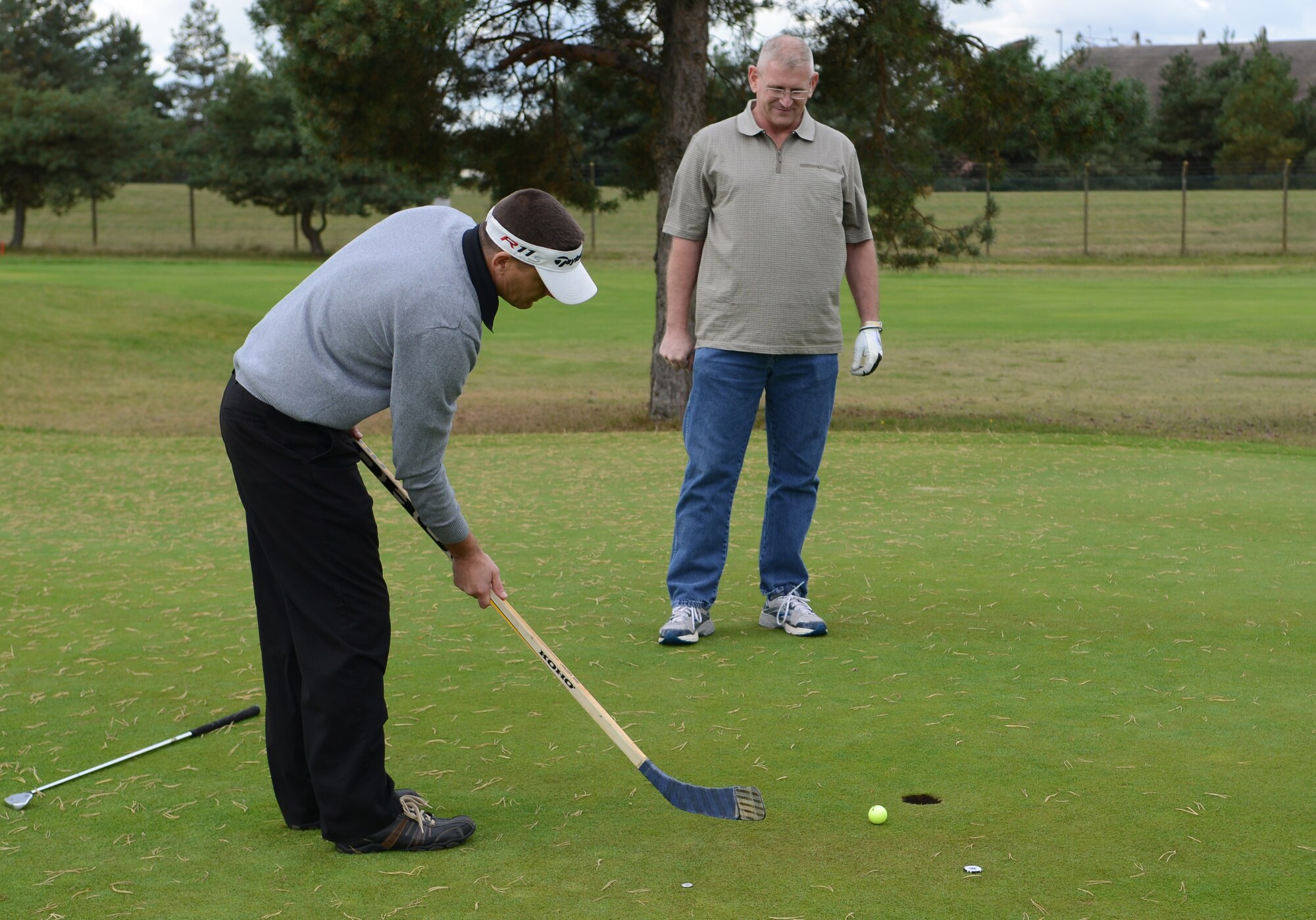 U.S. Air Force Chief Master Sgt. Tracy Jones, left, 100th Air Refueling Wing command chief, putts with a hockey stick during the Chiefs vs. Eagles golf tournament Sept. 24, 2014, at the Breckland Pines Golf Club on RAF Lakenheath, England. Each hole had a special stipulation, such as only using one club or driving the ball while seated. (U.S. Air Force photo/Airman 1st Class Dillon Johnston/Released)