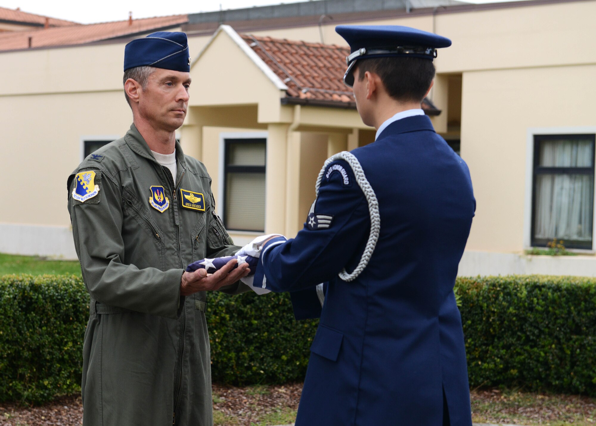 Col. Gregory Kreuder, 31st Fighter Wing vice commander, receives an American flag from Senior Airman Hector Chacon, 31st Force Support Squadron Honor Guard member, during a retreat ceremony, Sept. 25, 2014, at Aviano Air Base. Retreat gathered Airmen to reflect on the Prisoner of War/Missing in Action remembrance week and what the events symbolize. (U.S. Air Force photo/Airman 1st Class Deana Heitzman) 