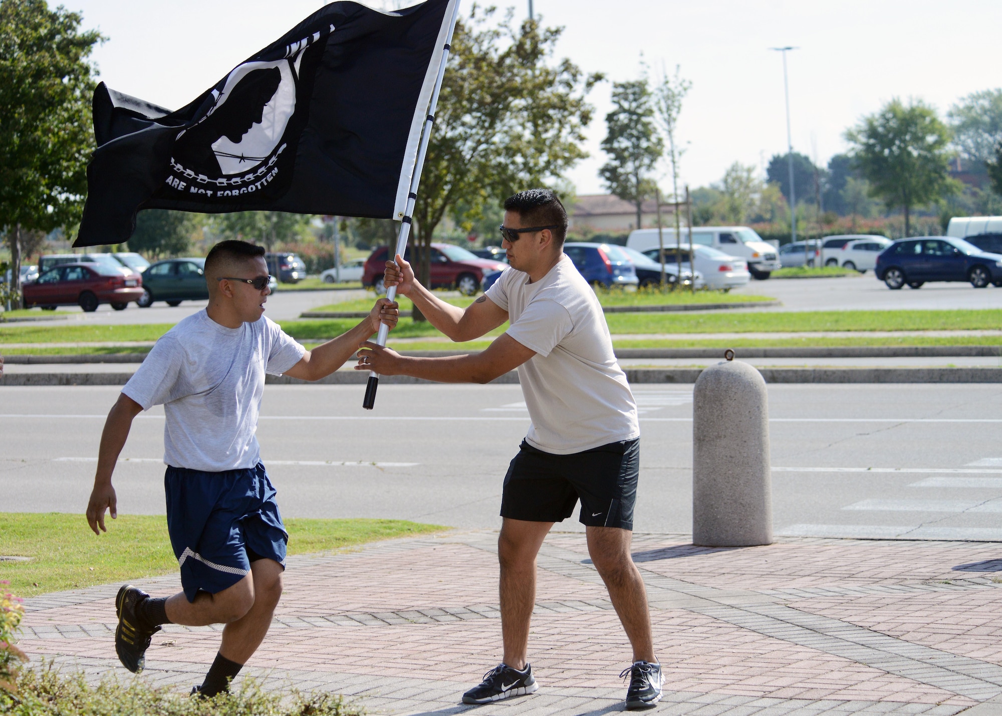 (From left) Senior Airman David Bustria, 31st Logistics Readiness Squadron vehicle maintainer, hands the Prisoner of War/Missing in Action flag to Mario Soriano, 31st Security Forces Squadron investigator, during a POW/MIA memorial run. The memorial run lasted from 7:30 a.m. to 4:45 p.m., which participants kept the flag moving to remember those who were a POW/MIA. (U.S. Air Force photo/Airman 1st Class Deana Heitzman)  