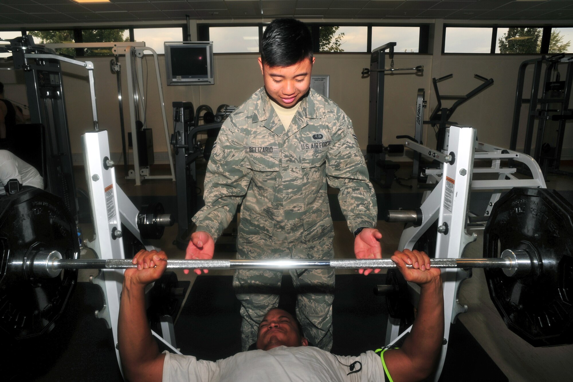 U.S. Air Force Airman 1st Class Jose Belizario, 100th Force Support Squadron fitness apprentice from Eastvale, Calif., spots U.S. Air Force Staff Sgt. Tracy Ross-Best, 95th Reconnaissance Squadron aerospace propulsion craftsman from Washington D.C., while he bench presses weight at the Hardstand Fitness Center Sept. 23, 2014, on RAF Mildenhall, England. Belizario earned the Square D Spotlight for exhibiting the Air Force Core Value of Excellence in All We Do. (U.S. Air Force photo/Senior Airman Christine Griffiths/Released)