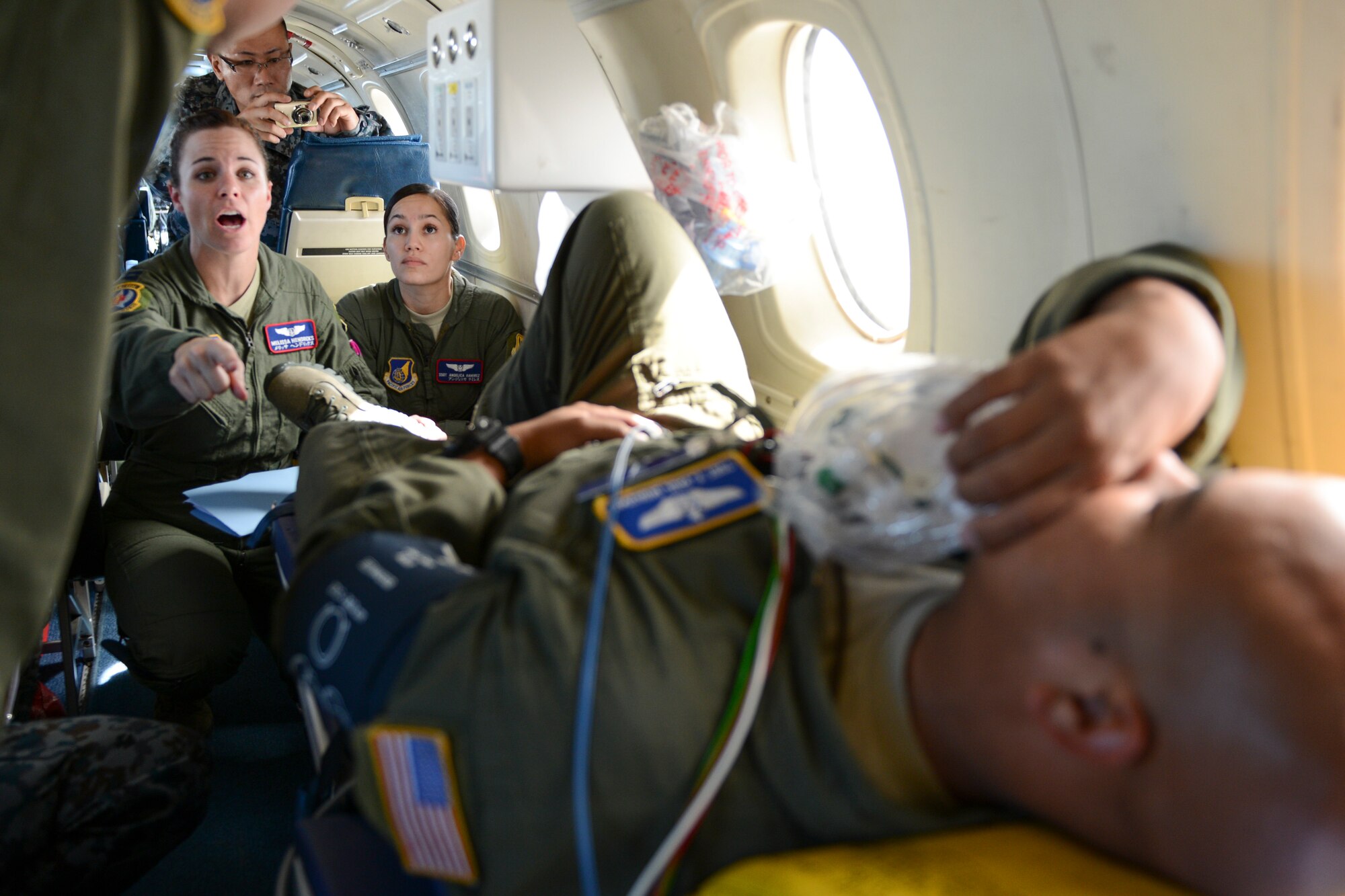U.S. Air Force Capt. Melissa Hendricks (Left), 18th Aeromedical Evacuation Squadron flight commander, shouts to be heard over C-12 engines during a medical evacuation training scenario over Kadena Air Base, Japan, Sept. 24, 2014. The 459th Airlift Squadron flew the medical crew, allowing Japan Air Self-Defense Force and Pacific Air Force command members to observe the flight. (U.S. Air Force photo by Staff Sgt. Cody H.Ramirez/Released)