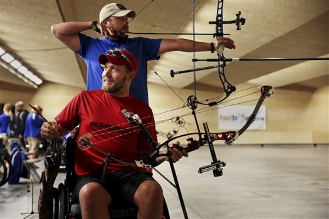 Marine Cpl. Richard Stalder, front, discusses shots during archery practice as Marine Sgt. Clayton McDaniel, back, aims at a target before the start of the Warrior Games at the Olympic Training Center in Colorado Springs, Colo., Sept. 24, 2014.