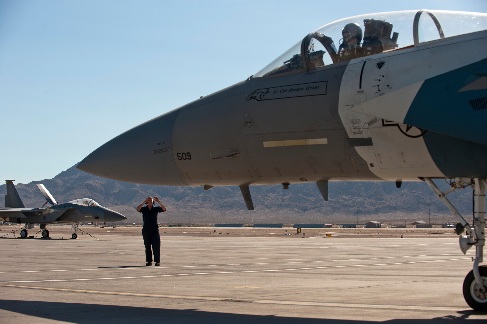 Staff Sgt. Justin White signals to Maj. Sam Joplin to begin taxiing a 65th Aggressor Squadron F-15 Eagle to the runway Sept. 18, 2014, at Nellis Air Force Base Nev. The roles and responsibilities of the 65th AGRS, deactivated Sept. 26, 2014, will be filled by the 64th AGRS. White is a crew chief with the 757th Aircraft Maintenance Squadron’s Flanker Aircraft Maintenance Unit and Joplin is an F-15 pilot with the 122nd Fighter Squadron at Naval Air Station Joint Reserve Base New Orleans. (U.S. Air Force photo/Airman 1st Class Thomas Spangler)