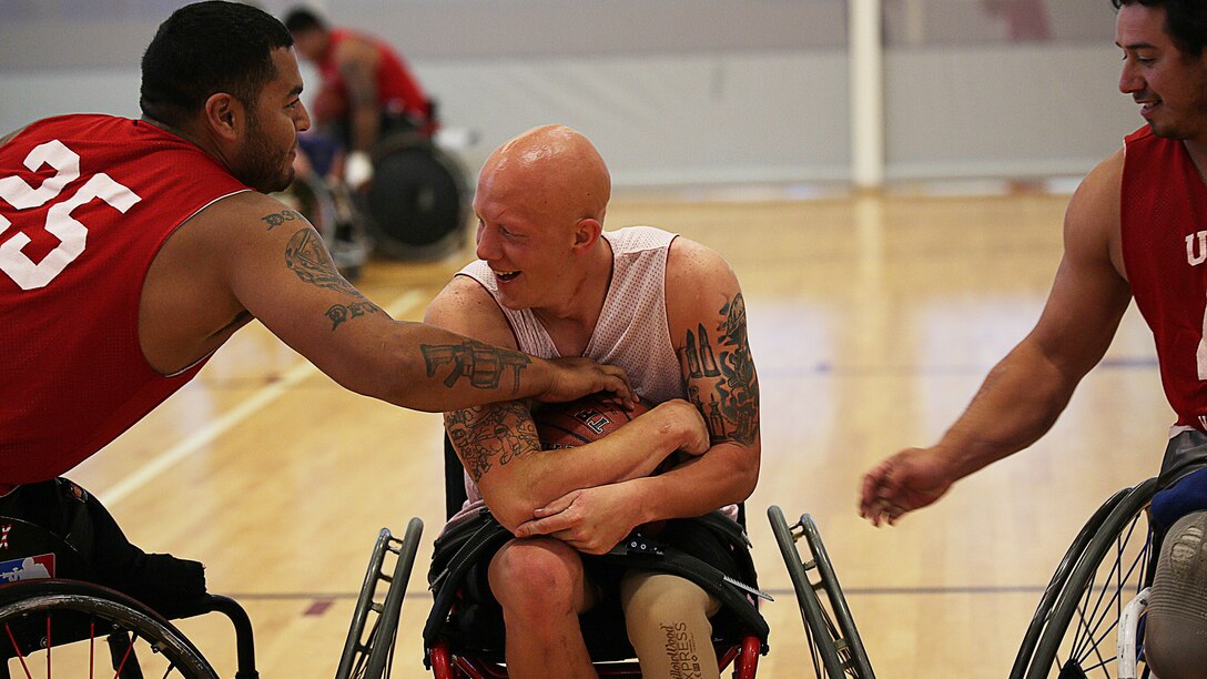 Pfc. Erik Webb (center) from Grand Prairie, Texas, fights for the basketball against Cpl. Jorge Salazar (left) and Sgt. Eric Rodriguez (right) during practice for the Marine team, Sept. 25, in preparation for the 2014 Warrior Games. The Marine team has been training since September 15 in order to build team cohesion and acclimate to the above 6,000 feet altitude of Colorado Springs. The Marine team is comprised of both active duty and veteran wounded, ill and injured Marines who are attached to or supported by the Wounded Warrior Regiment, the official unit of the Marine Corps charged with providing comprehensive non-medical recovery care to wounded, ill and injured Marines. The Warrior Games are a Paralympic-style competition for more than 200 wounded, ill and injured service members and are taking place Sept. 28 to Oct. 4 at the Olympic Training Center in Colorado Springs, Colorado. Follow the Marine team's progress at www.facebook.com/wwr.usmc.