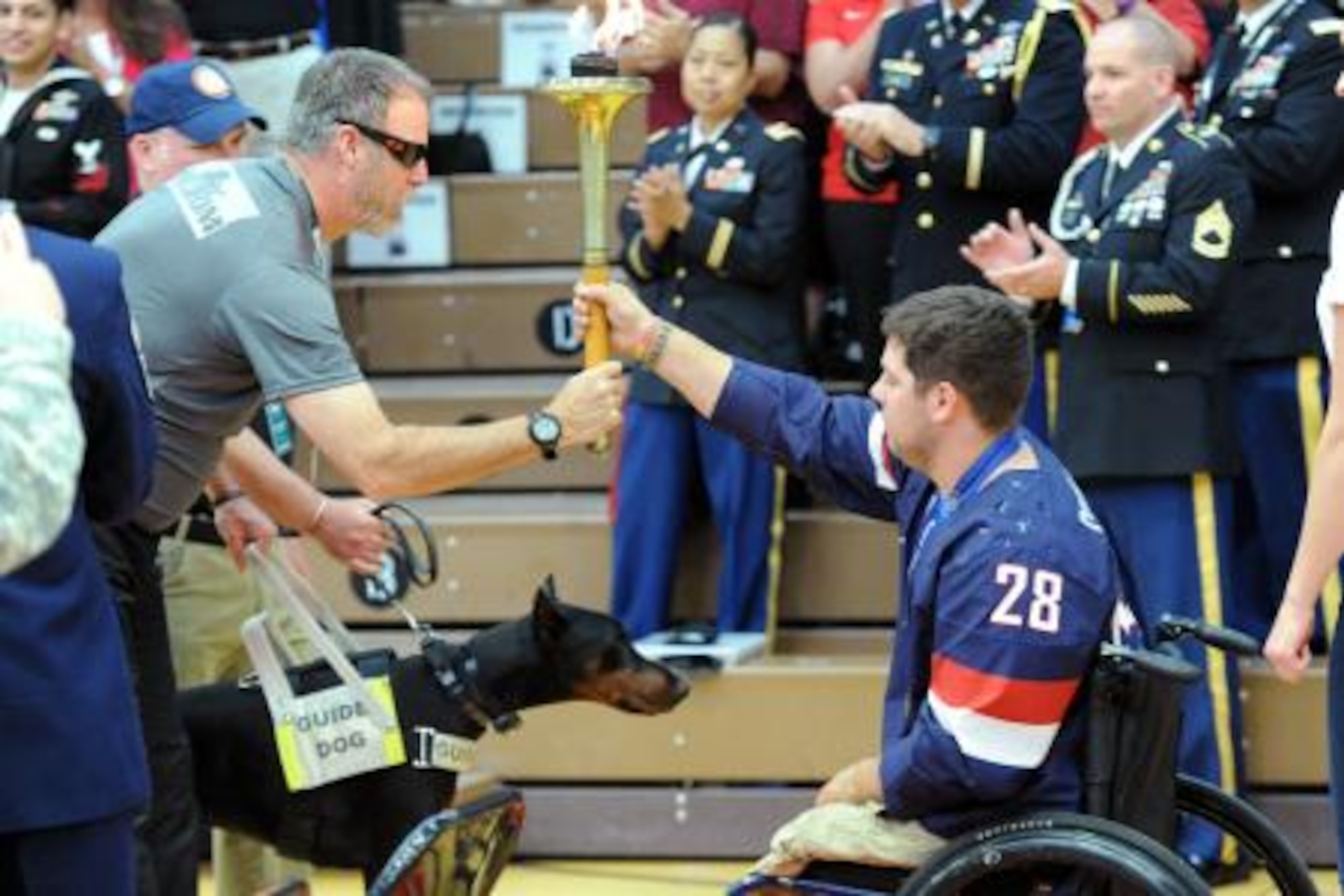 Army Sgt. First Class Doug Franklin of the Army Special Operations Command team passes the Olympic torch to retired Marine Cpl. Paul Schaus, who is a gold medal Paralympian, during the opening ceremony for the 2014 Warrior Games at the Olympic Training Center in Colorado Springs, Colo., Sept. 28, 2014. (DoD News photo by EJ Hersom)