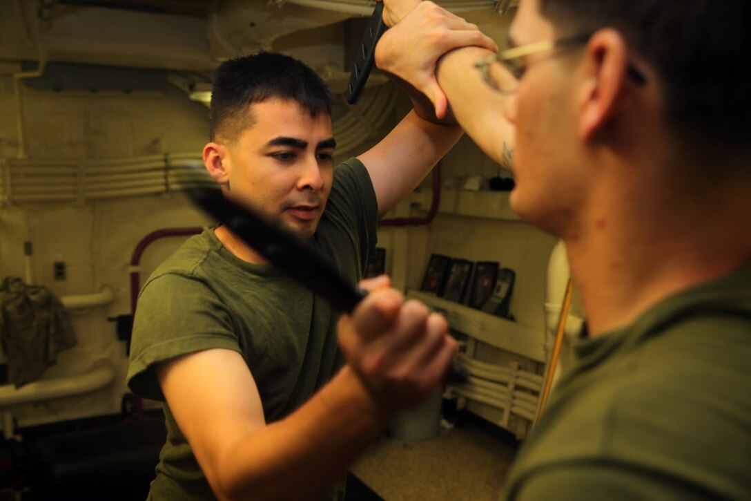 U.S. Marine Corps Sgt. Brendan S. Bigney, left, a chemical, biological, radiological, nuclear defense specialist with the 11th Marine Expeditionary Unit (MEU), and a native of Sacramento, California, uses a training knife to practice slashing techniques on Sgt. Andrew S. DiMauro, 1st Air Naval Gunfire Liaison detachment, 11th MEU, a radio operator and native of Burlington, Connecticut, during Marine Corps Martial Arts Program training aboard the USS San Diego (LPD 22), Sept. 26. Marines from the 11th MEU are deployed with the Makin Island Amphibious Ready Group as a flexible, adaptable and persistent force in the U.S. 5th Fleet area of responsibility. 
 (U.S. Marine Corps photo by Cpl. Jonathan R. Waldman/Released)
