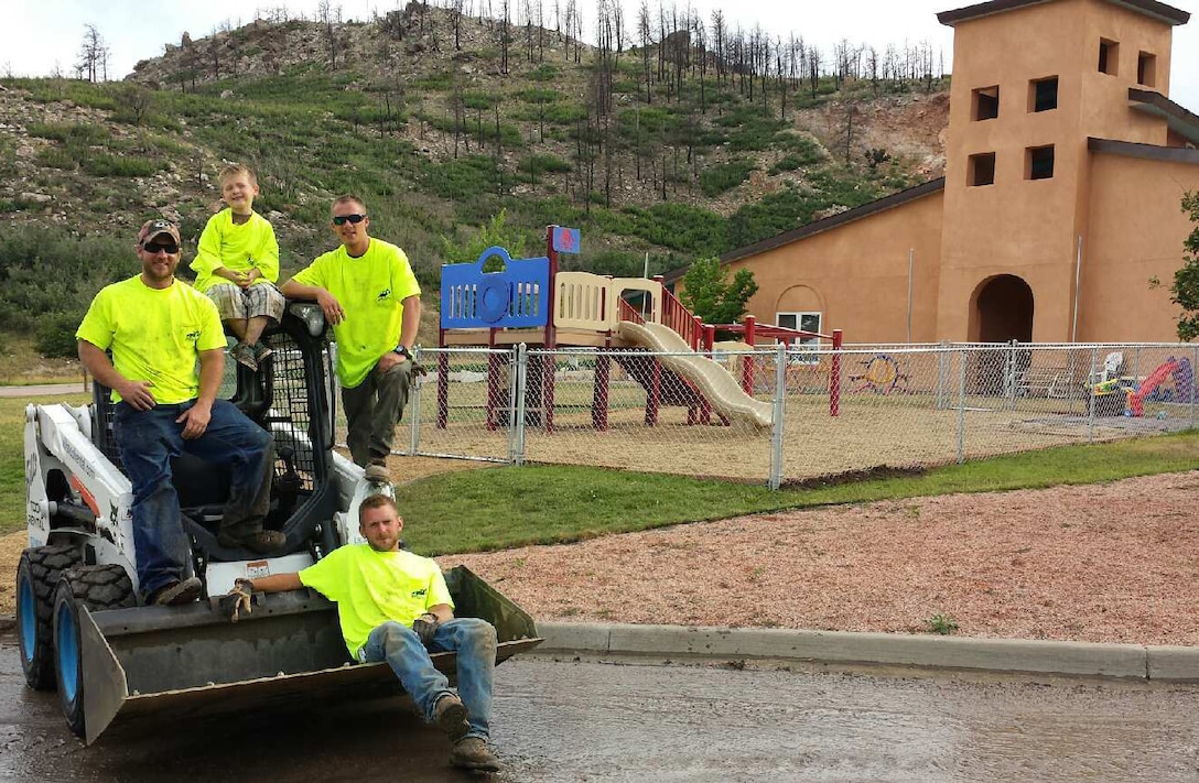 Contractor employees who volunteered for the project relax 
after 10 hours on Sunday--their handiwork stands in the background.