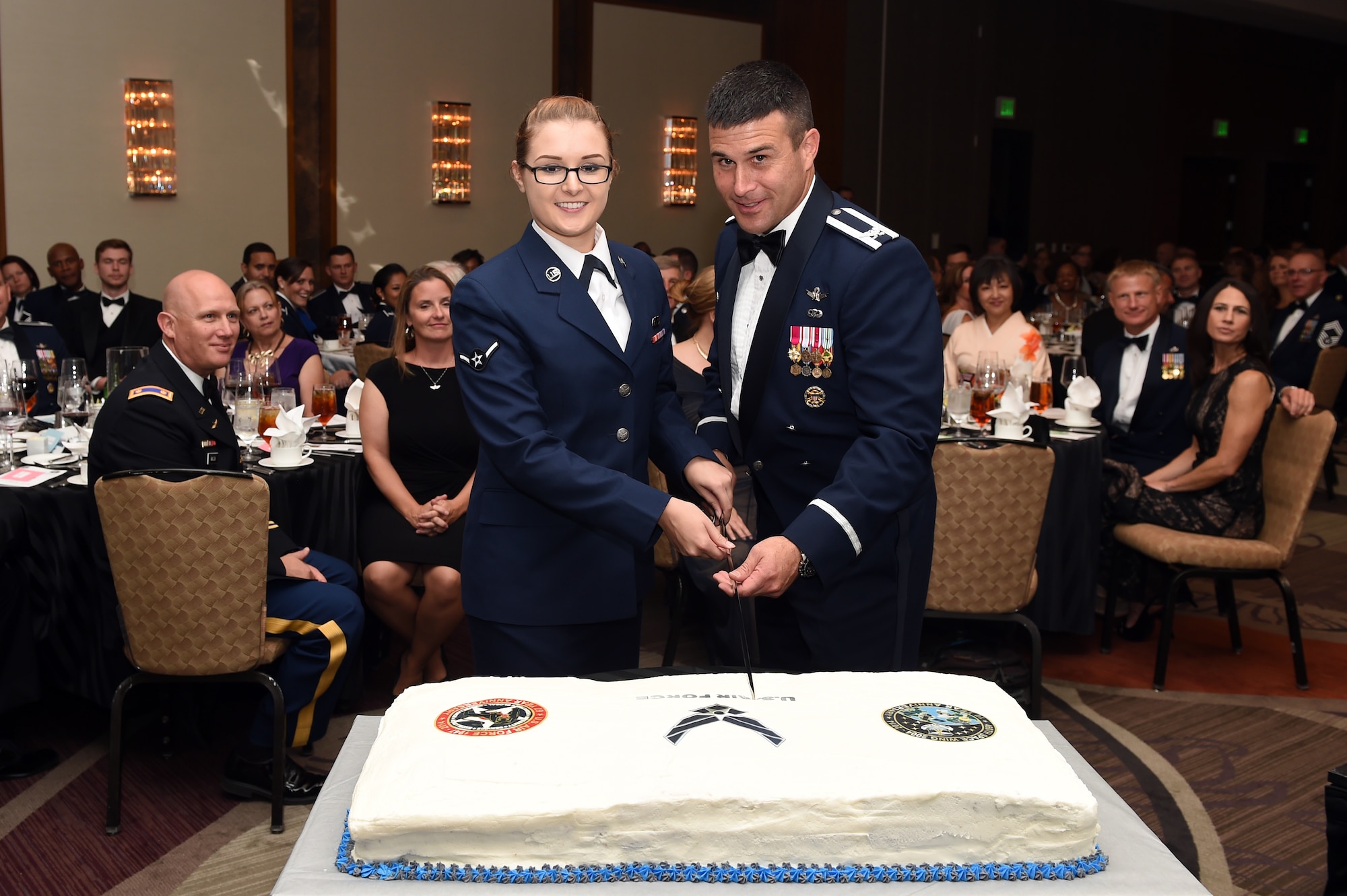 Airman Emily E. Amyotte, 460th Space Wing Public Affairs photojournalist, left, and Col. John Wagner, 460th Space Wing commander, cut the cake during the Air Force Ball and 460th Space Wing 10th anniversary celebration Sept. 27, 2014, at the Grand Hyatt Hotel in Denver. Every year, the Air Force celebrates its birthday with a formal military ball and festivities many people remember for a lifetime. Buckley Air Force Base did their part to wish the Air Force and the 460th SW a happy birthday with dinner, a guest speaker and a nighttime celebration. (U.S. Air Force photo by Airman Emily E. Amyotte/Released)