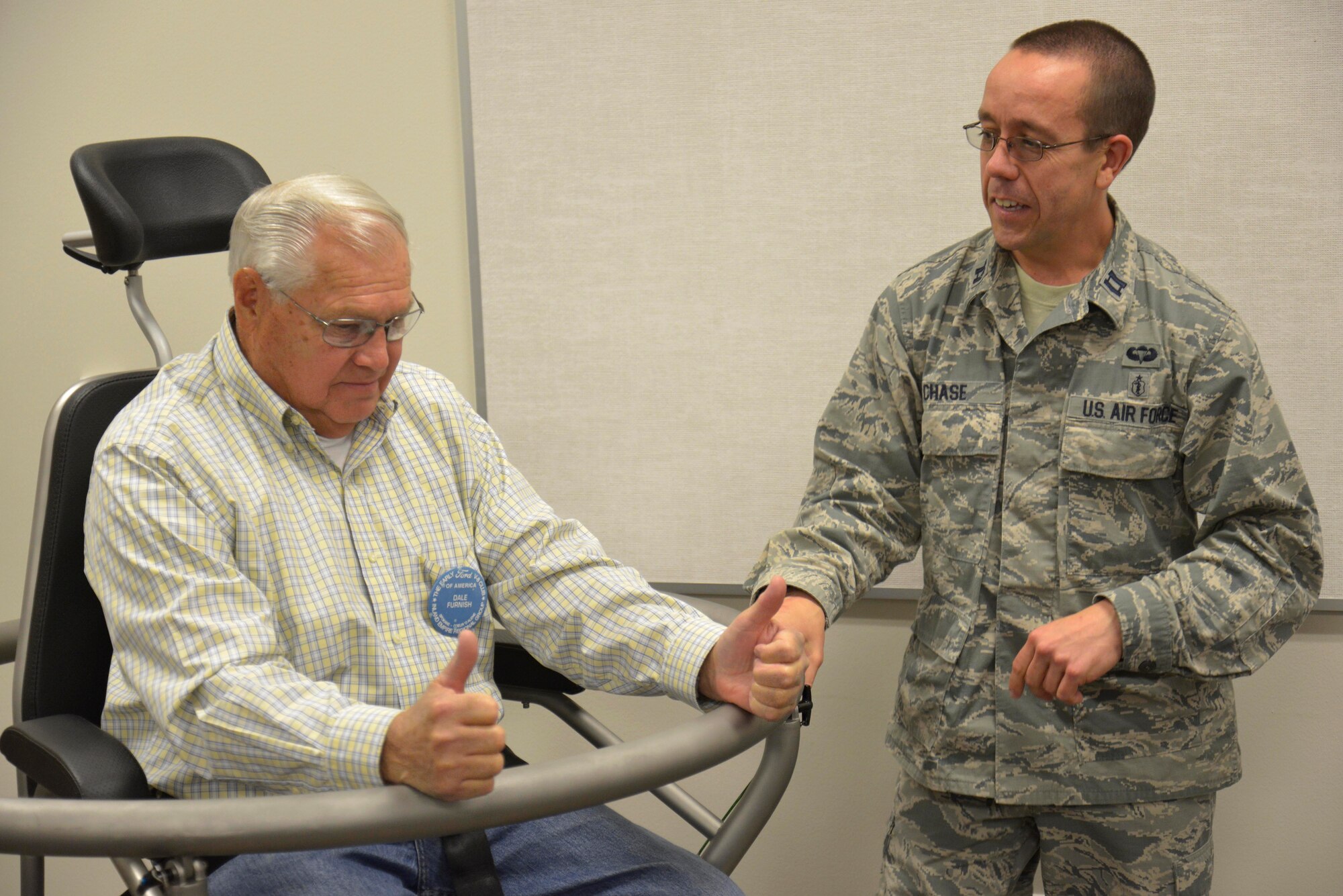 Capt. Eric Chase, 92nd Aerospace Medicine Squadron aerospace and operational physiology team chief, instructs Dale Furnish, a member of the Early Ford V-8 Club, on the effects of the Barany chair during a base tour at Fairchild Air Force Base, Washington, Sept. 26, 2014. The Barany chair is a training tool that helps Airmen understand spatial disorientation and learn to trust their instruments. (U.S. Air Force photo by Airman 1st Class Janelle Patiño/Released)