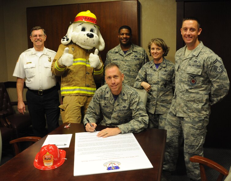 Col. Tom Wilcox, 341st Missile Wing commander, signs the 2014 Fire Prevention Week Proclamation on Sept. 26. (From left) Daniel Dodson, 341st Civil Engineer Squadron deputy fire chief; Sparky the Fire Dog; Chief Master Sgt. Phillip Easton, 341st MW command chief; Col. Marné Deranger, 341st MW vice commander; and Senior Master Sgt. Joshua Trundle, 341st CES fire chief, stand by. Fire Prevention Week starts Oct. 5 and runs through Oct. 11 and will include a children’s fire truck ride, fire safety education briefings and displays, a fire truck parade and the fourth annual Fire Muster competition. This year’s theme, “Working smoke alarms save lives, test yours every month,” encourages all Americans to promote fire prevention awareness inside of the home and at work. (U.S. Air Force photo/Airman 1st Class Joshua Smoot) 