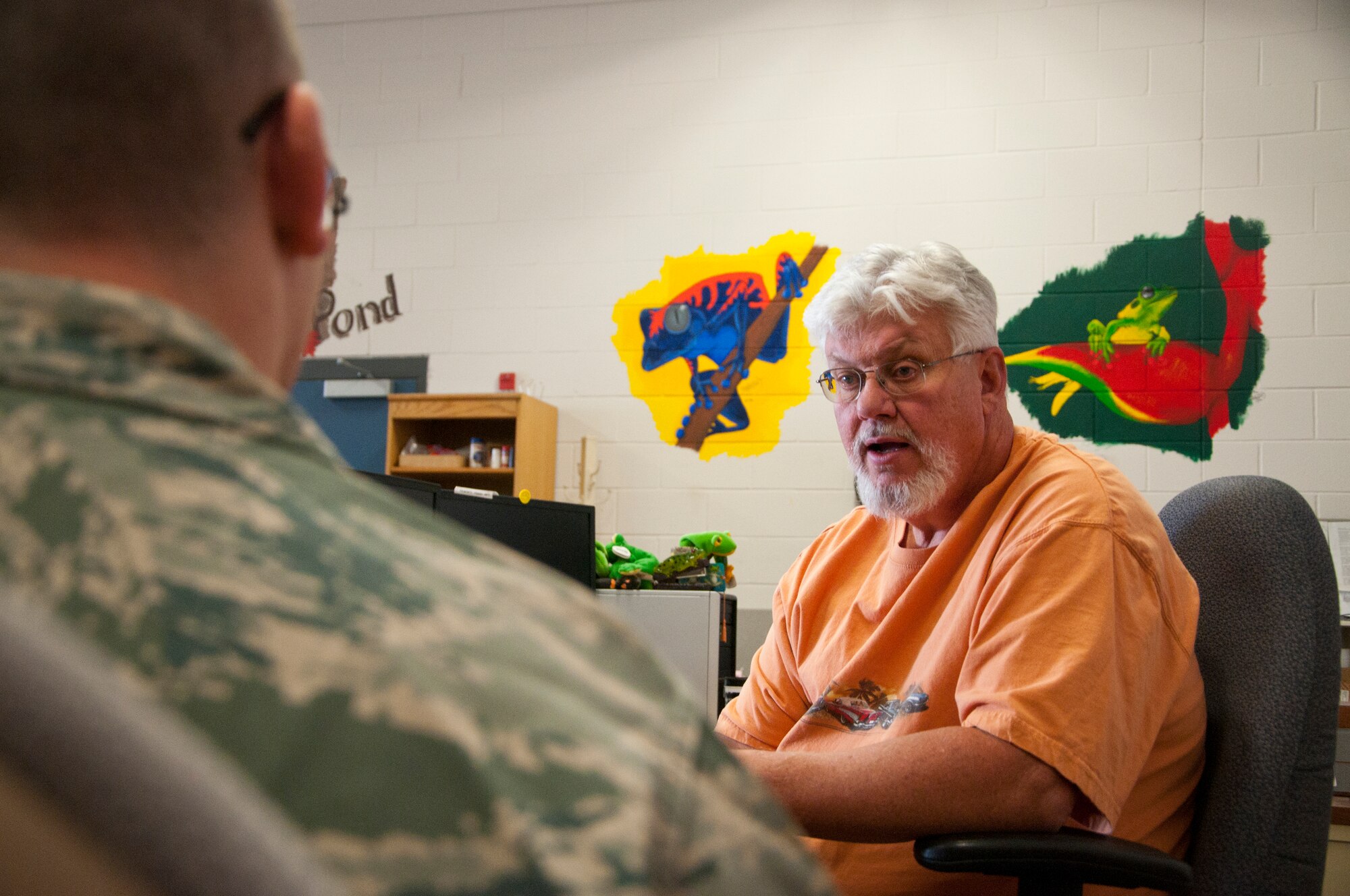 Tech. Sgt. (Ret.) David Austin, 90th Maintenance Operations Squadron Missile Maintenance Material Control Supply technician supervisor, talks with Tech. Sgt. Jason Giguere, 90th Logistics Readiness Squadron pickup and delivery NCO-in-charge, Sept. 8, 2014, in the 90th Maintenance Group High Bay Material Control Shop. Austin decorates the shop with murals in hopes of making it a place where Airmen can relax during downtime. (U.S. Air Force photo by Airman 1st Class Jason Wiese)