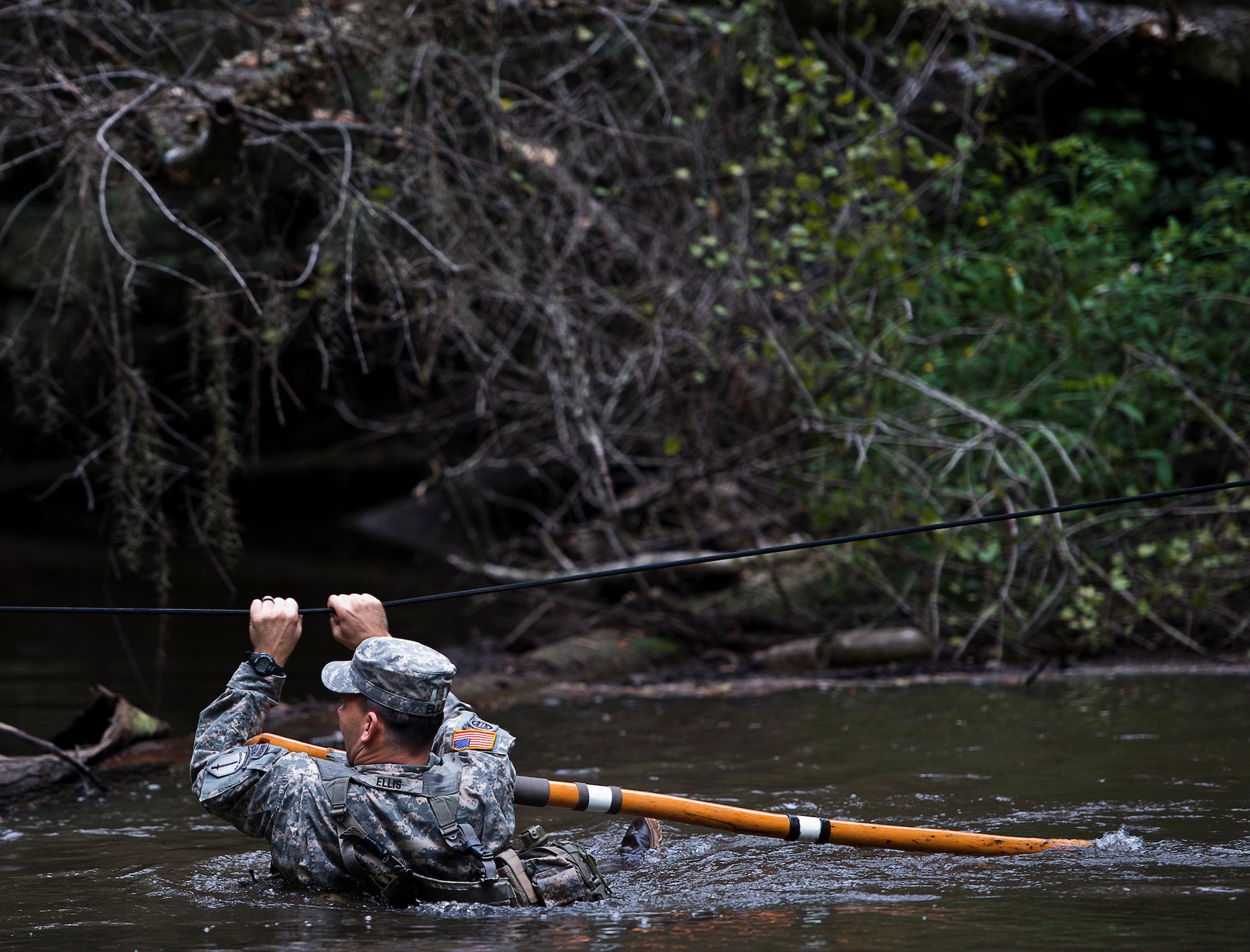 Sgt. 1st Class Travis Ellis, 6th Ranger Training Battalion, crosses the river using a rope to reach a memorial on Eglin Air Force Base, Fla., for the four fallen Rangers who lost their lives Feb. 16, 1995.  More than 40 Soldiers participated in the excursion Sept. 25 that followed in the footsteps of the tragic squad to learn from their experience and understand what took place that night almost 20 years ago.  (U.S. Air Force photo/Samuel King Jr.)