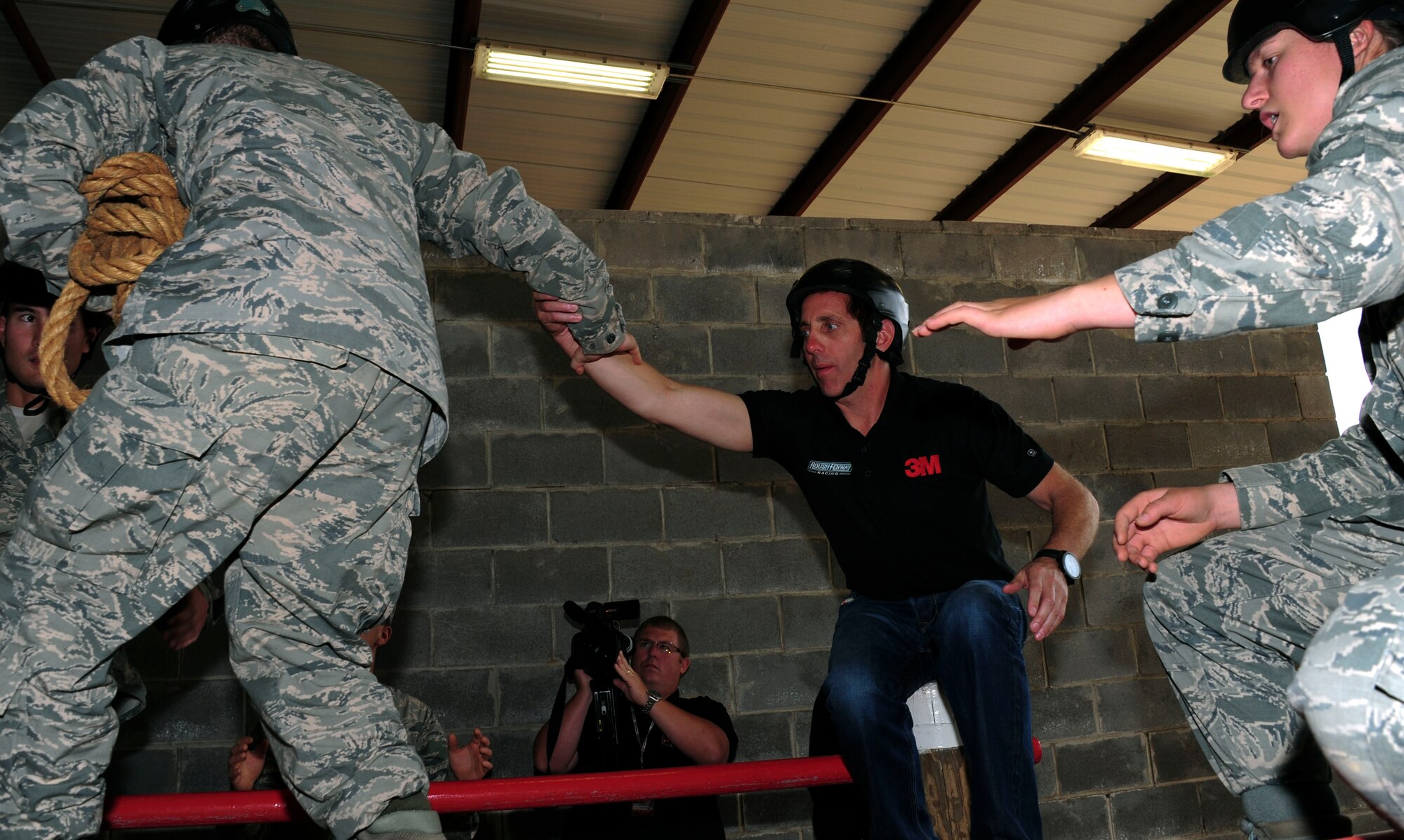 Greg Biffle, NASCAR driver, helps an Airman across an obstacle at Project X, an Officer Training School leadership reaction course, at Maxwell Air Force Base, Ala., Sep. 25, 2014. Biffle expressed his support of the military and the troops during his visit. (U.S Air Force photo by Airman 1st Class Alexa Culbert)
