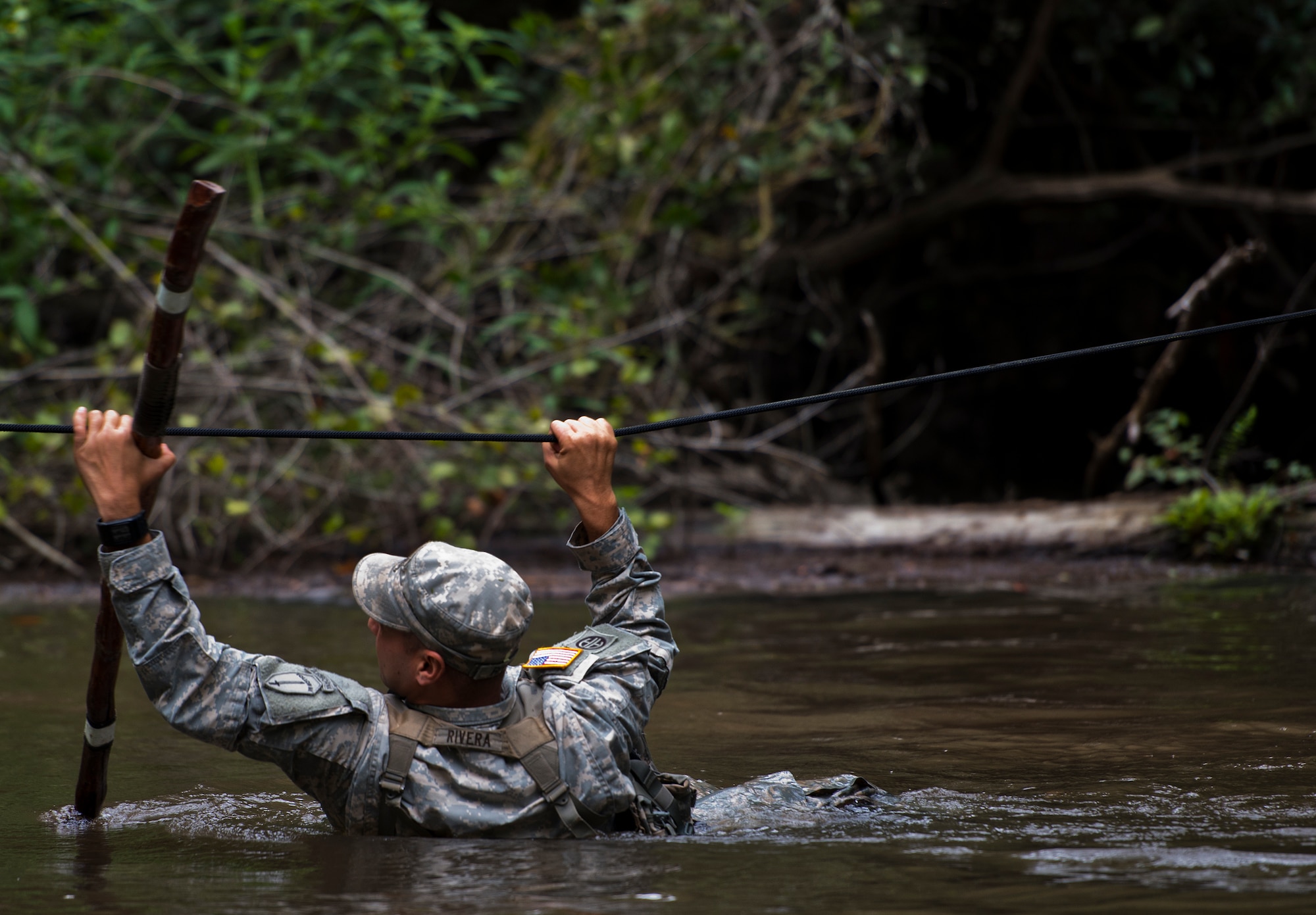 Staff Sgt. Ariel Rivera, 6th Ranger Training Battalion, crosses the river using a rope to reach a memorial on Eglin Air Force Base, Fla., for the four fallen Rangers who lost their lives Feb. 16, 1995.  More than 40 Soldiers participated in the excursion Sept. 25 that followed in the footsteps of the tragic squad to learn from their experience and understand what took place that night almost 20 years ago.  (U.S. Air Force photo/Samuel King Jr.)