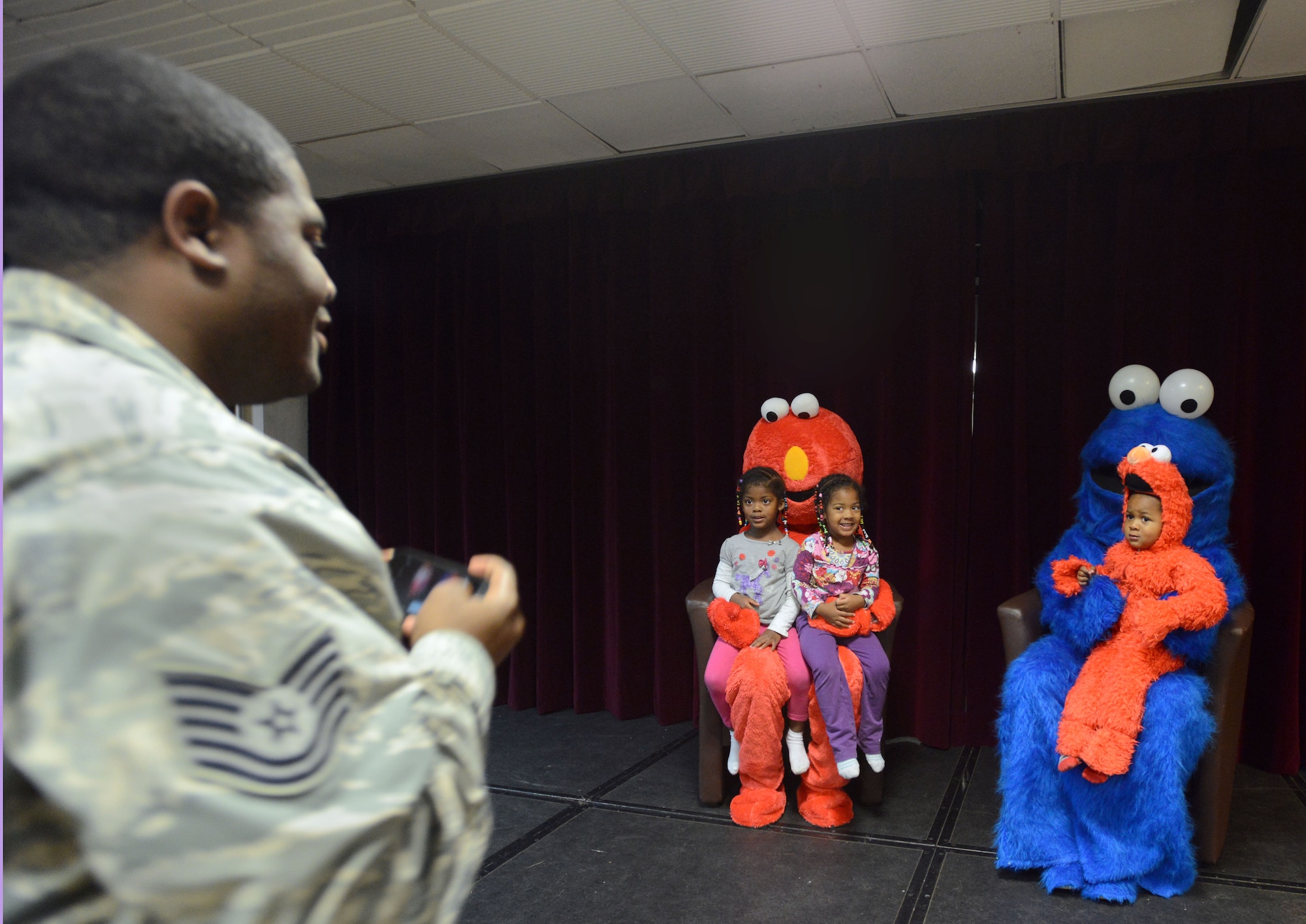Tech. Sgt. Andre Grant, U.S. Air Forces in Europe and Air Forces Africa, takes a photo of his children with Elmo and Cookie Monster during a family night hosted by the Ramstein Community Center at Ramstein Air Base, Germany, Sept. 22, 2014. The RCC hosts monthly family nights to give parents an opportunity to have a fun filled night with their children away from home. (U.S. Air Force photo/Senior Airman Timothy Moore)